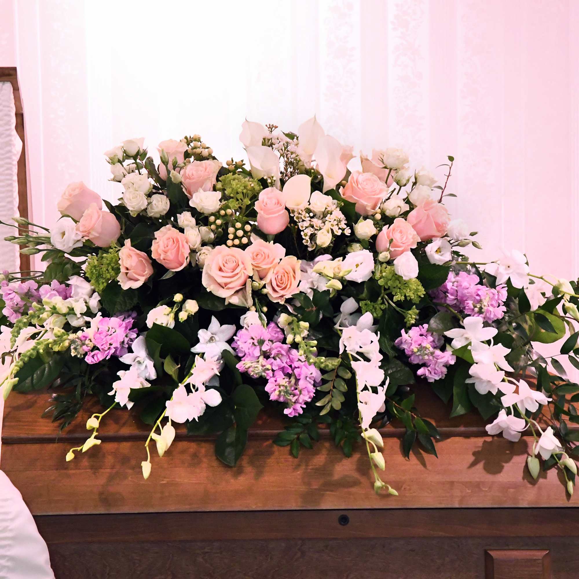 Large pink and white floral casket spray with trailing orchids
