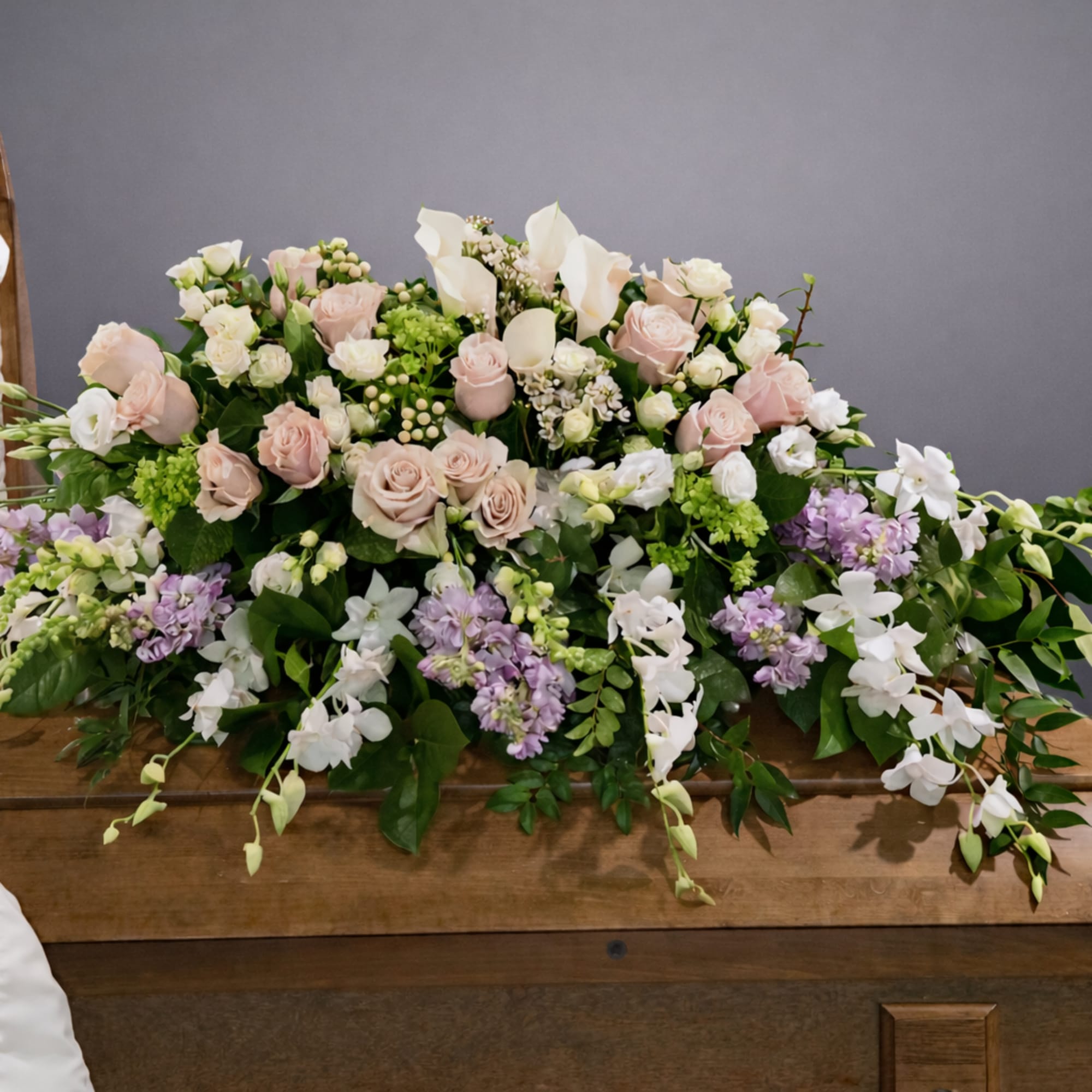 Pastel floral casket spray with roses, lilies, and orchids