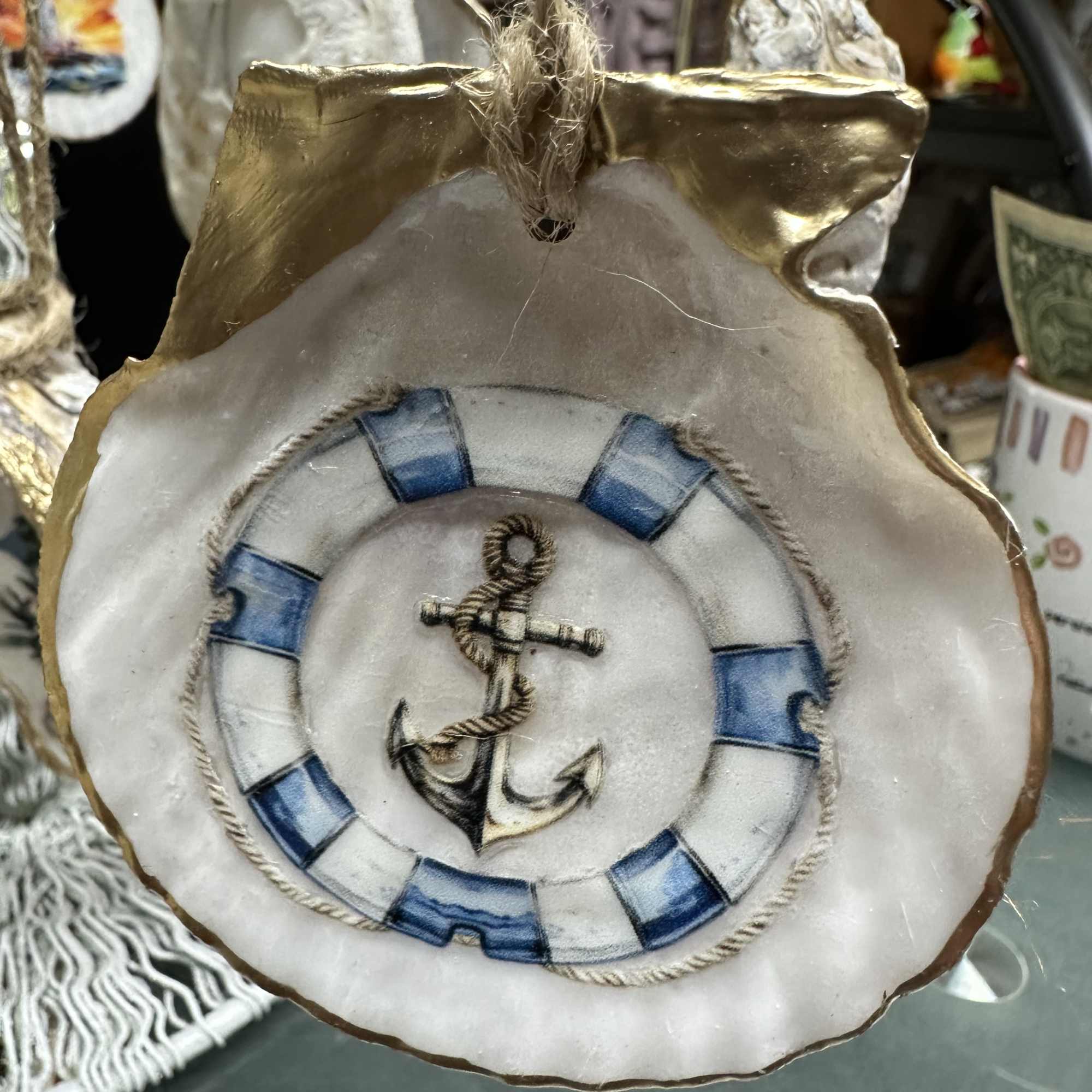 Decorative hanging ornament shaped like a shell with an anchor design