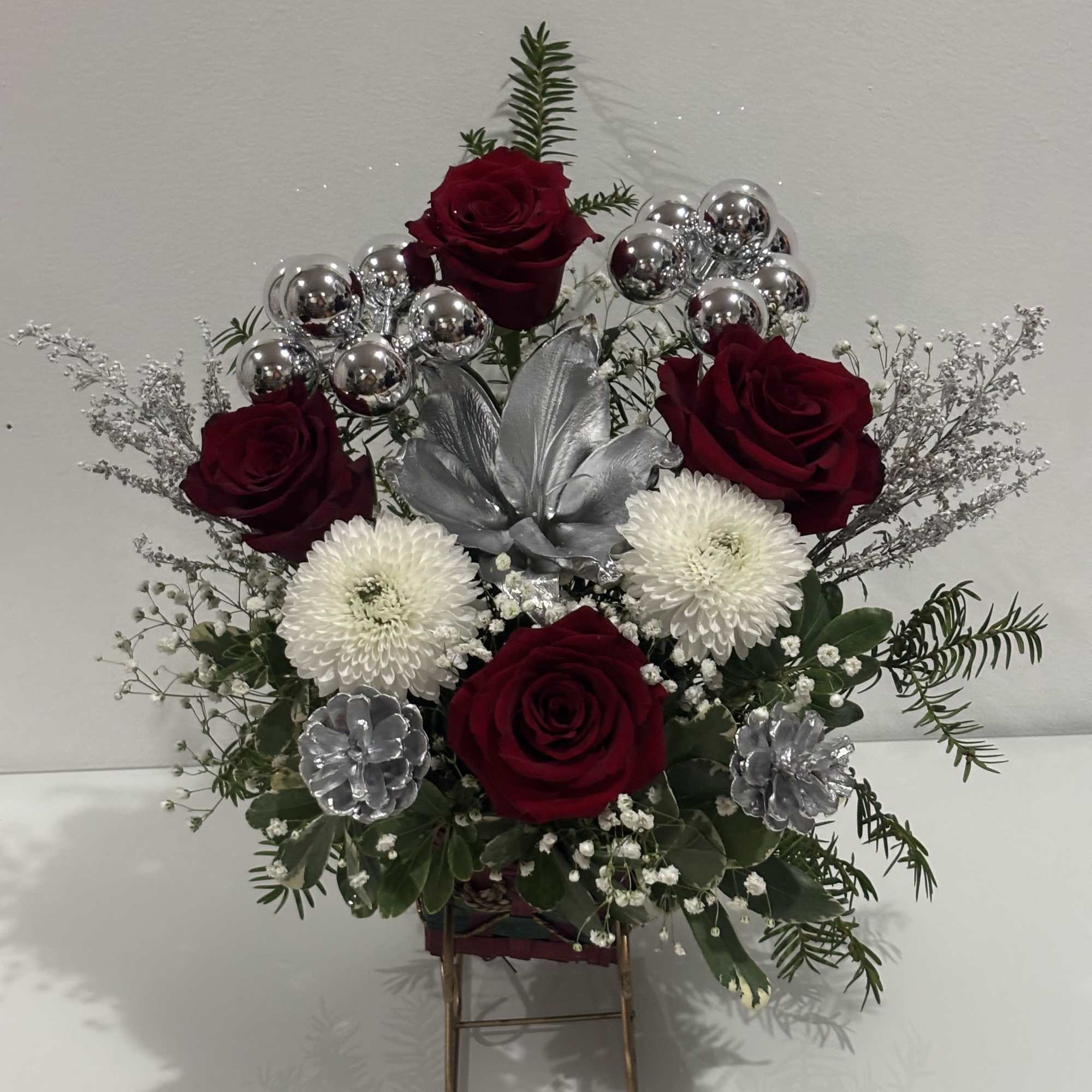 Arrangement of red roses and white mums with silver accents in a stand