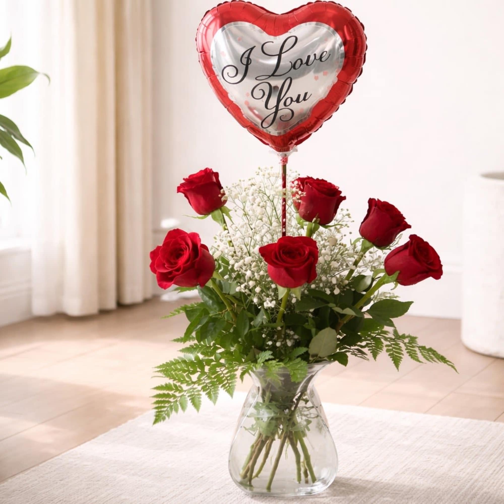 Red roses in a glass vase with a heart balloon that says I Love You