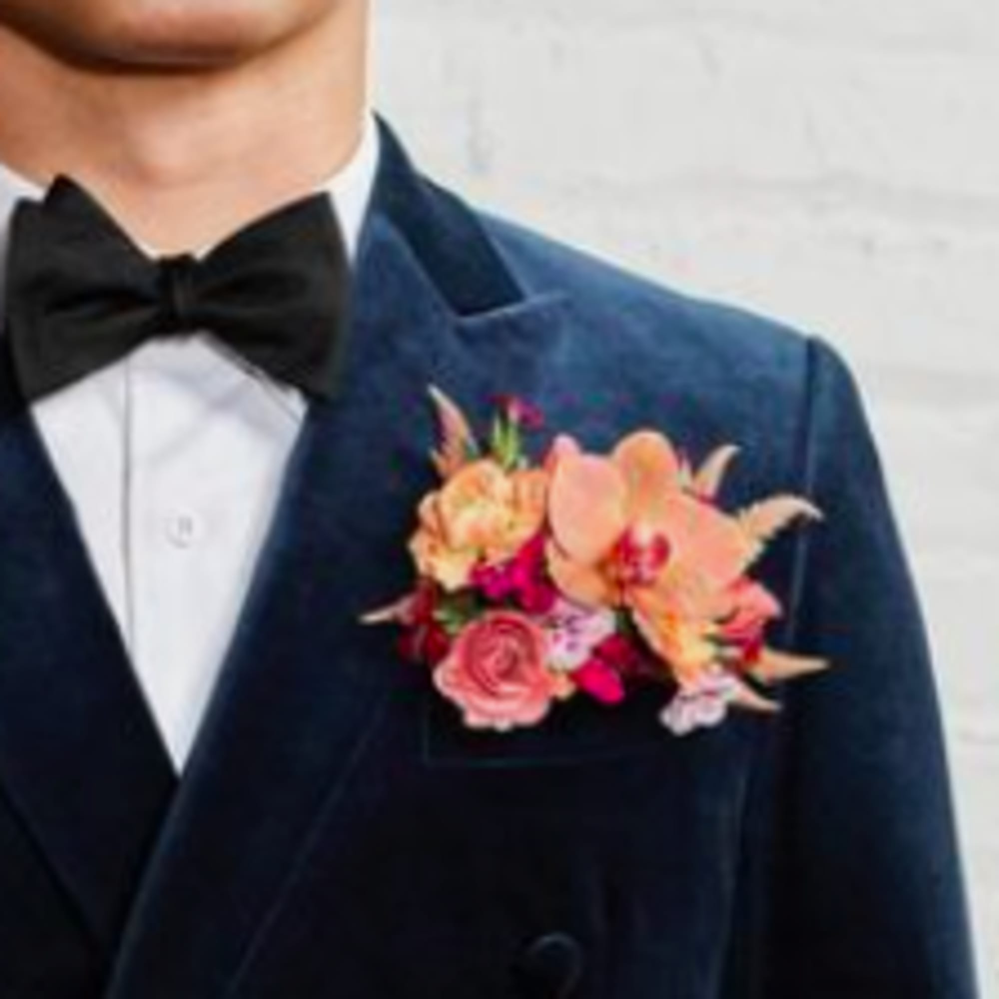 Boutonniere with pink and peach flowers on a navy suit lapel