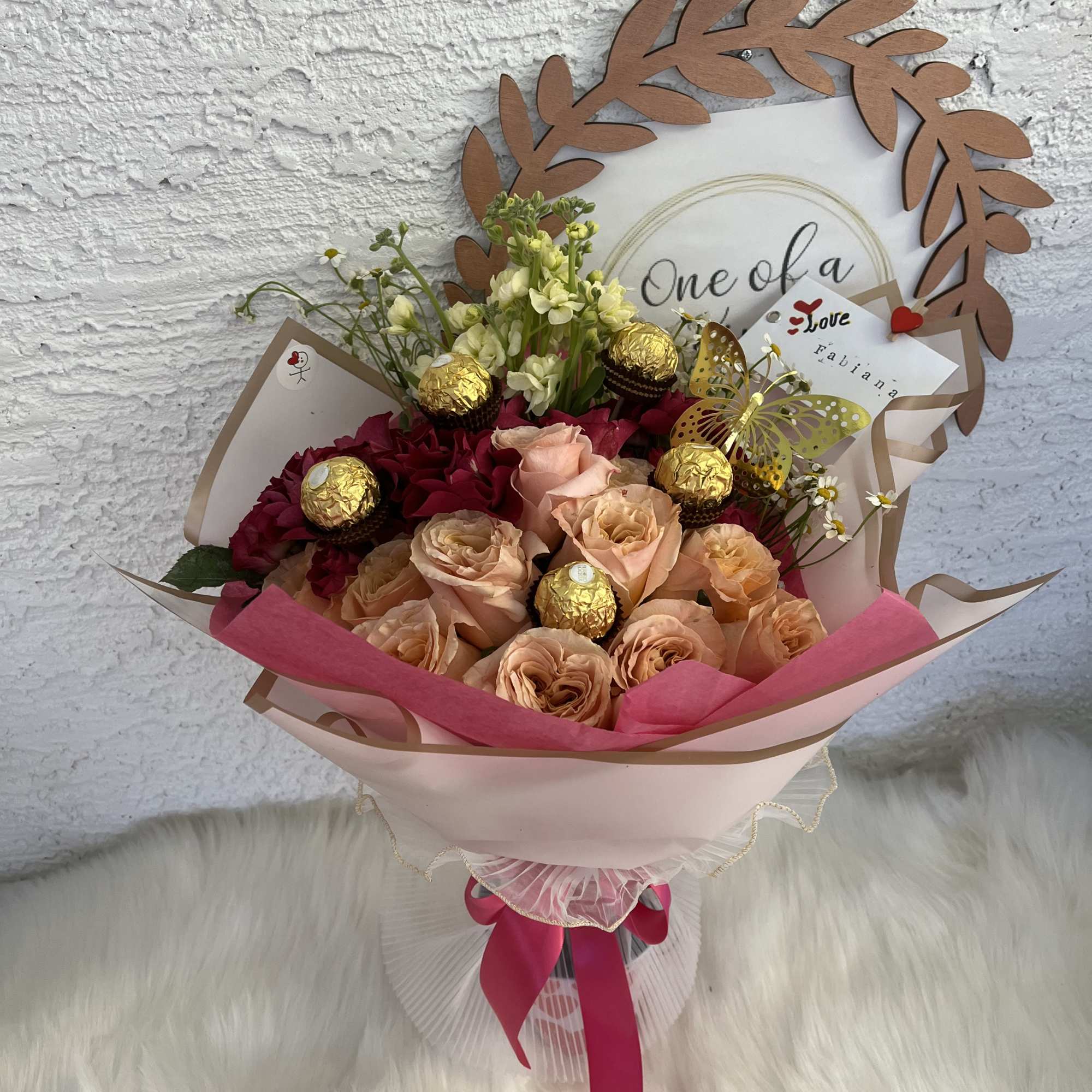Bouquet of peach and deep pink roses with gold chocolates and a butterfly pick