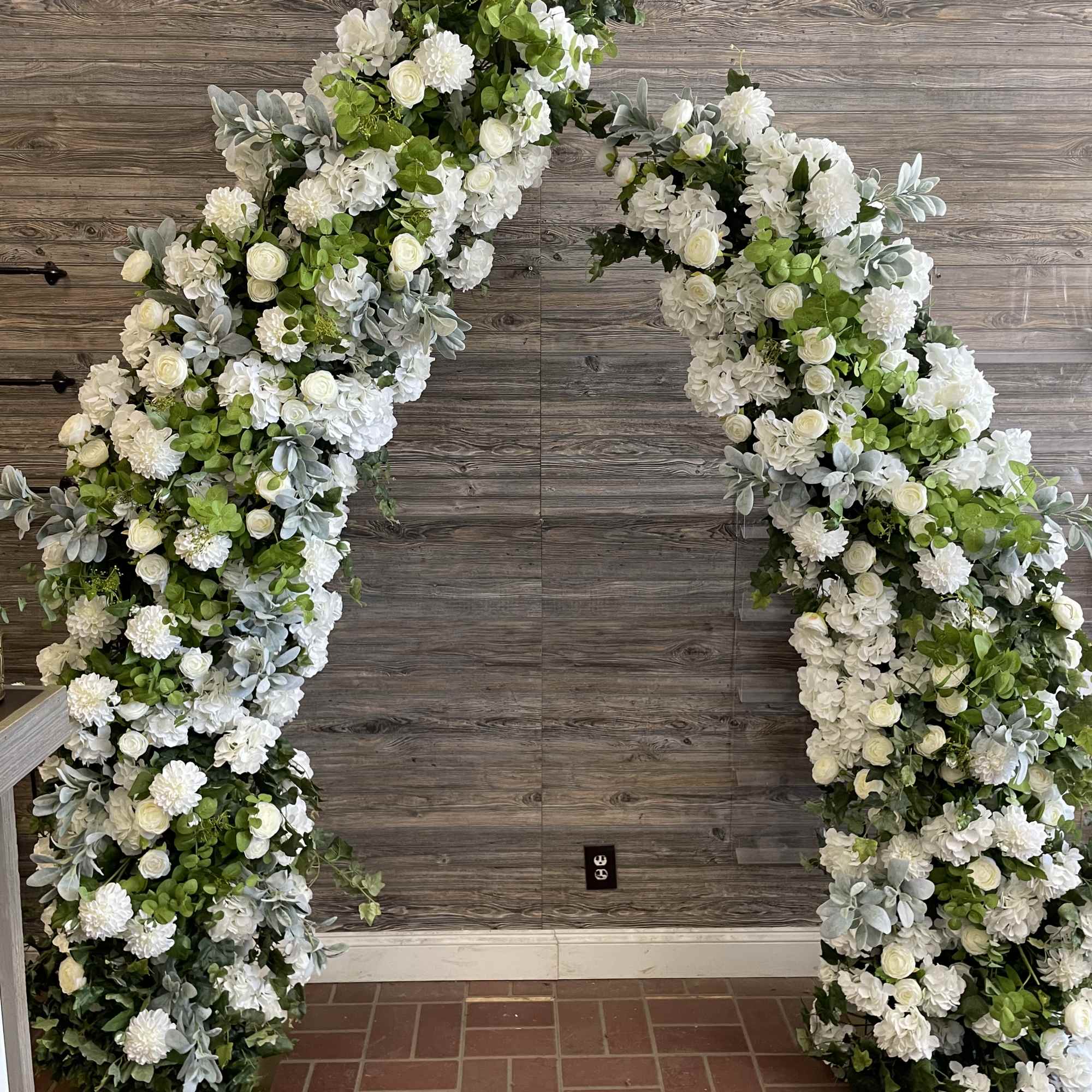 Large white floral arch with roses and hydrangeas