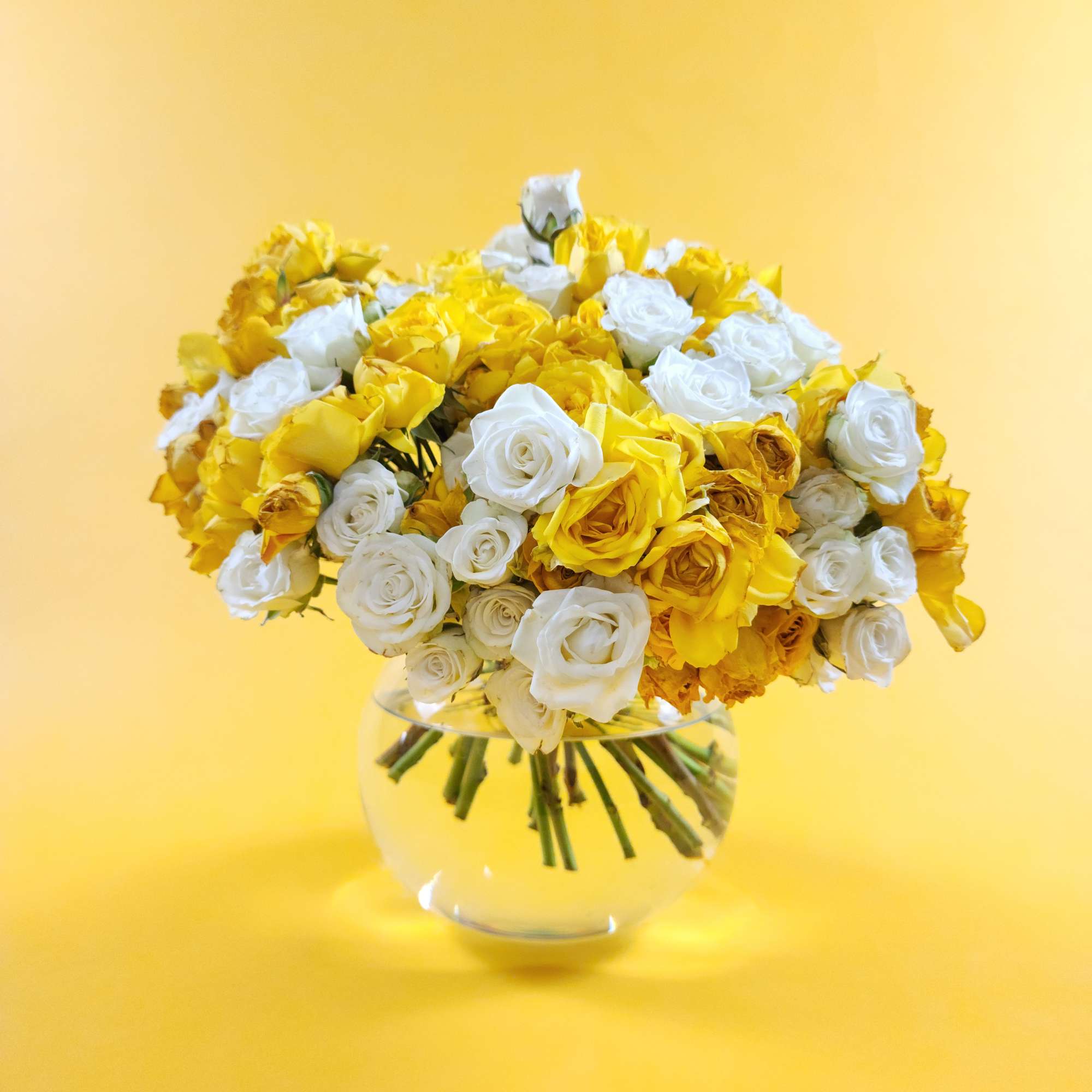 Bouquet of yellow and white roses in a clear glass vase