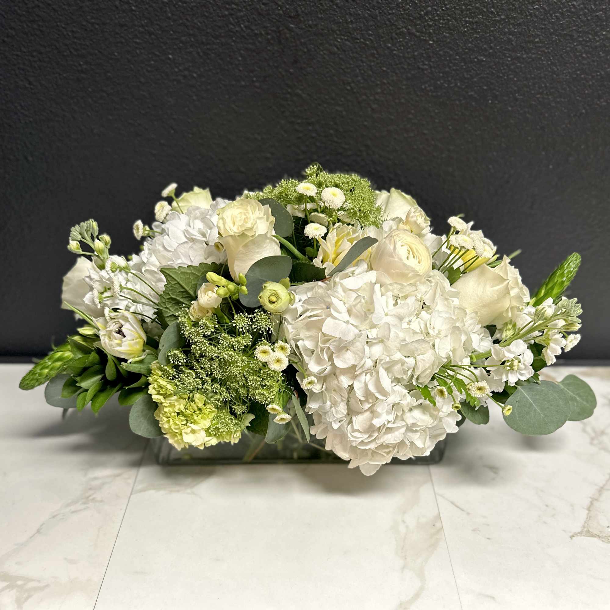 Low white floral arrangement in a rectangular glass vase