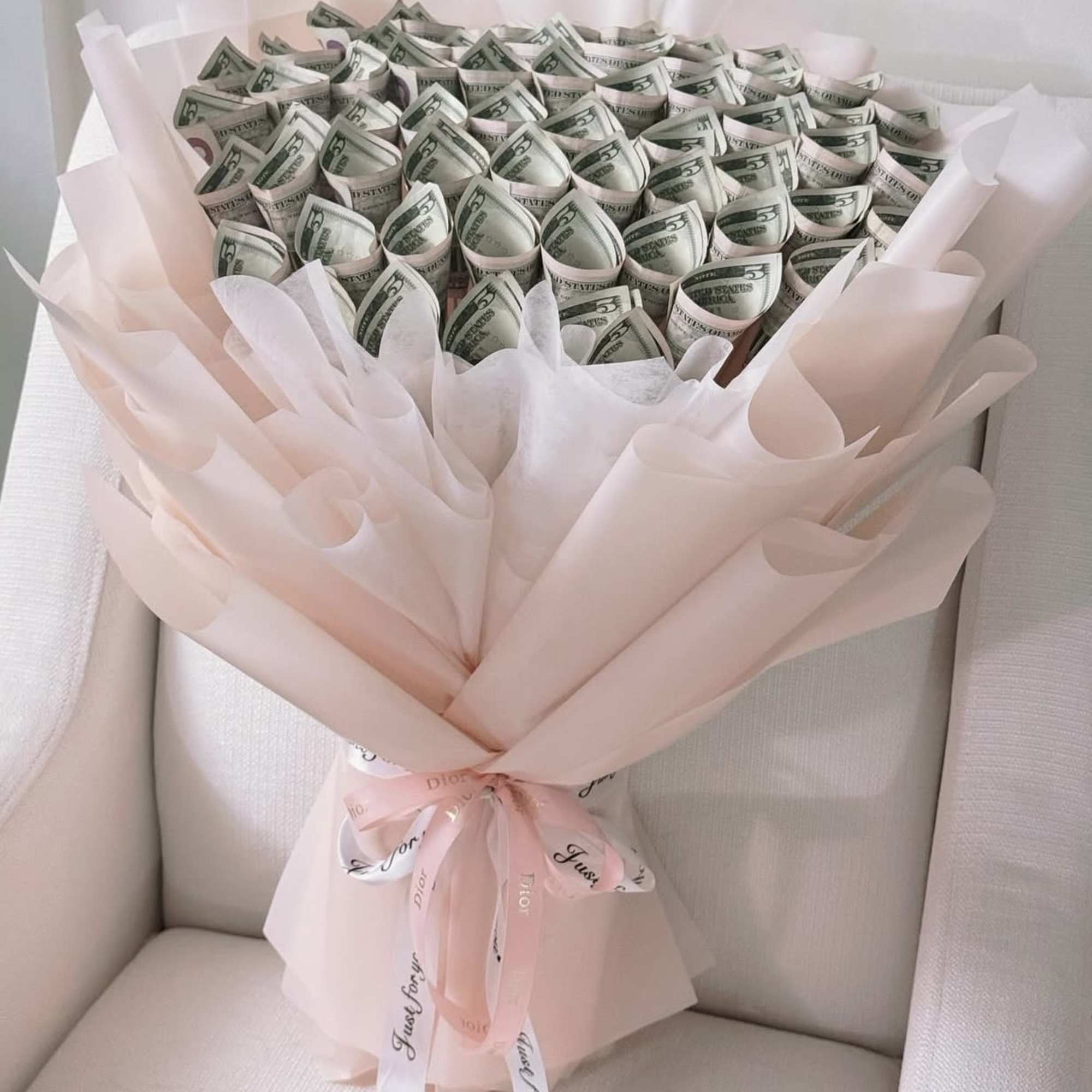 Bouquet of folded dollar bills wrapped in pale pink paper