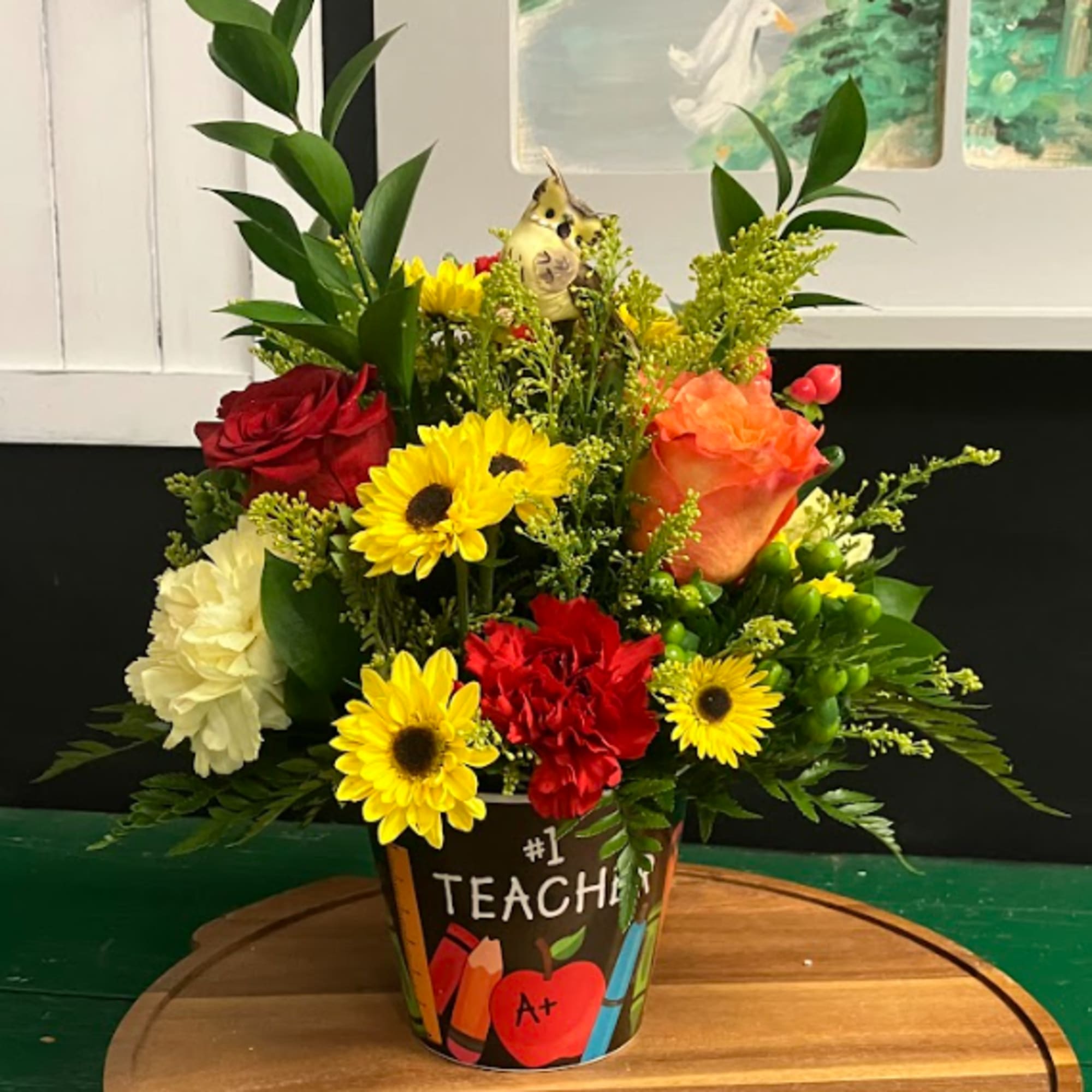 Colorful mixed flower arrangement in a teacher-themed pot