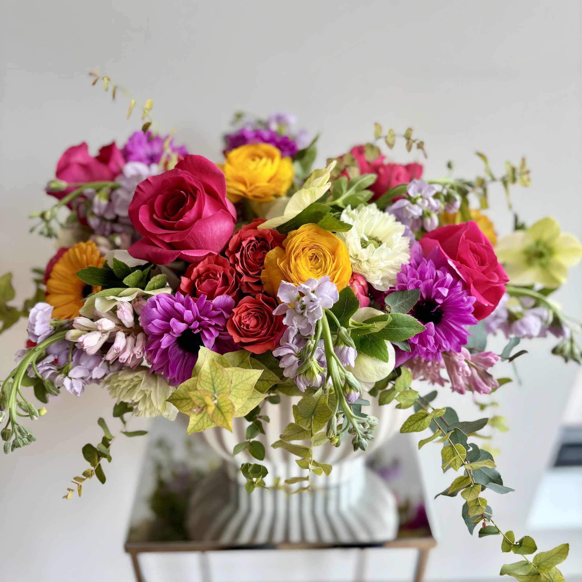 Mixed bouquet of roses and daisies in a white vase