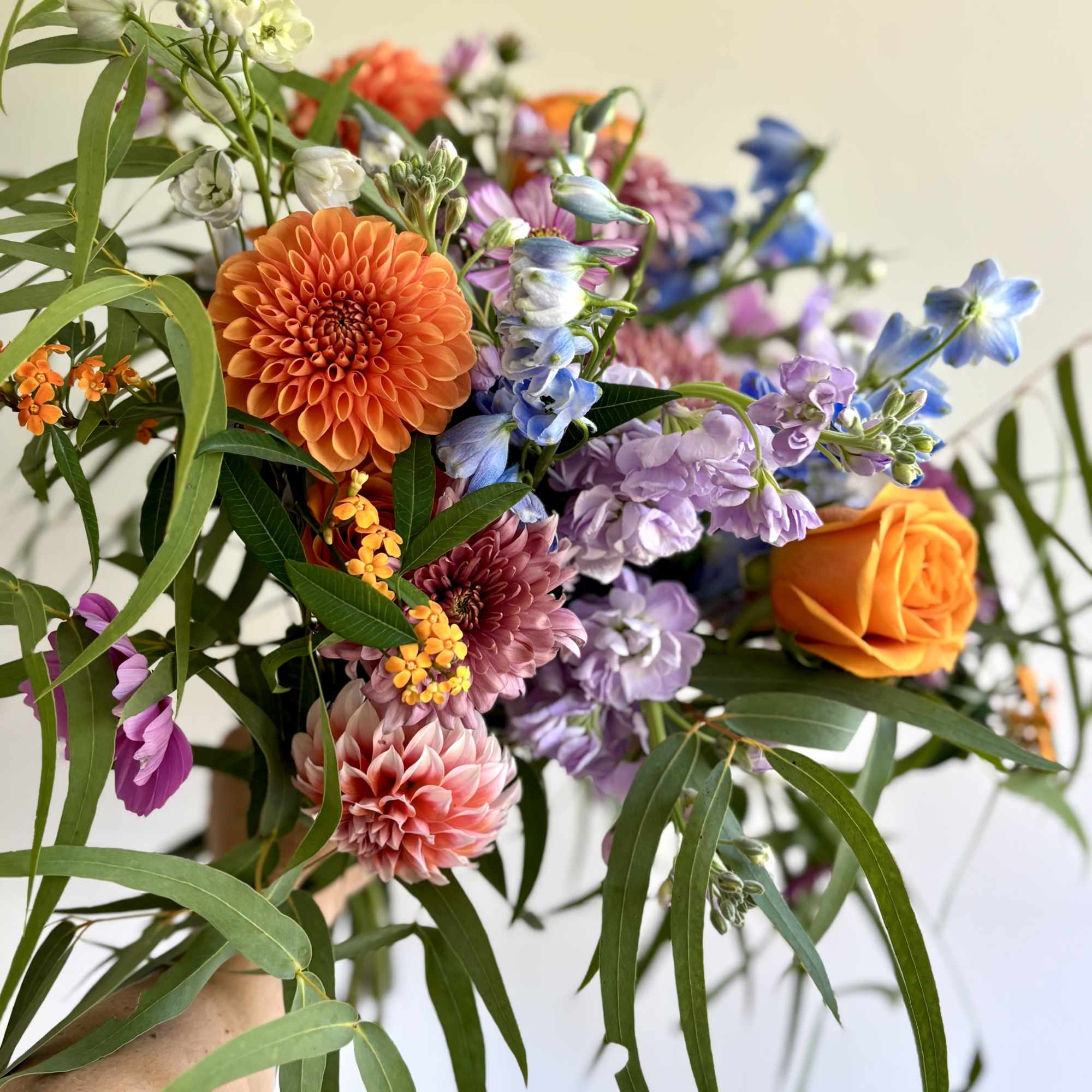 Handheld bouquet with orange, purple, pink, and blue flowers