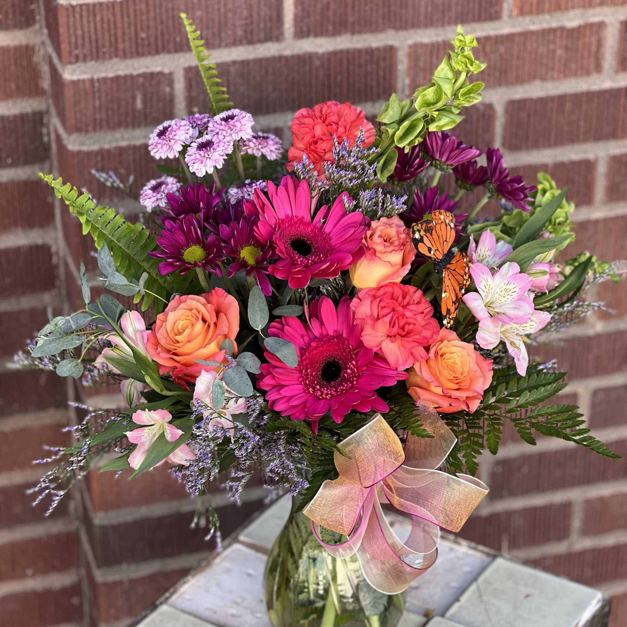 Mixed bouquet of pink, orange, and purple flowers in a glass vase