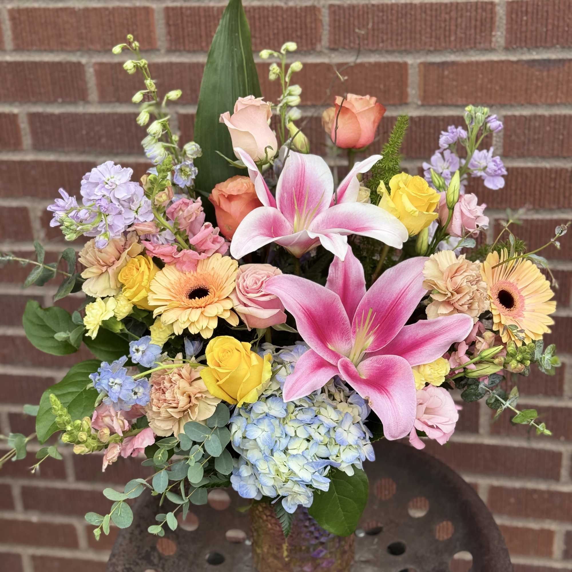 Mixed bouquet with pink lilies, roses, hydrangea, and gerbera daisies in a glass vase