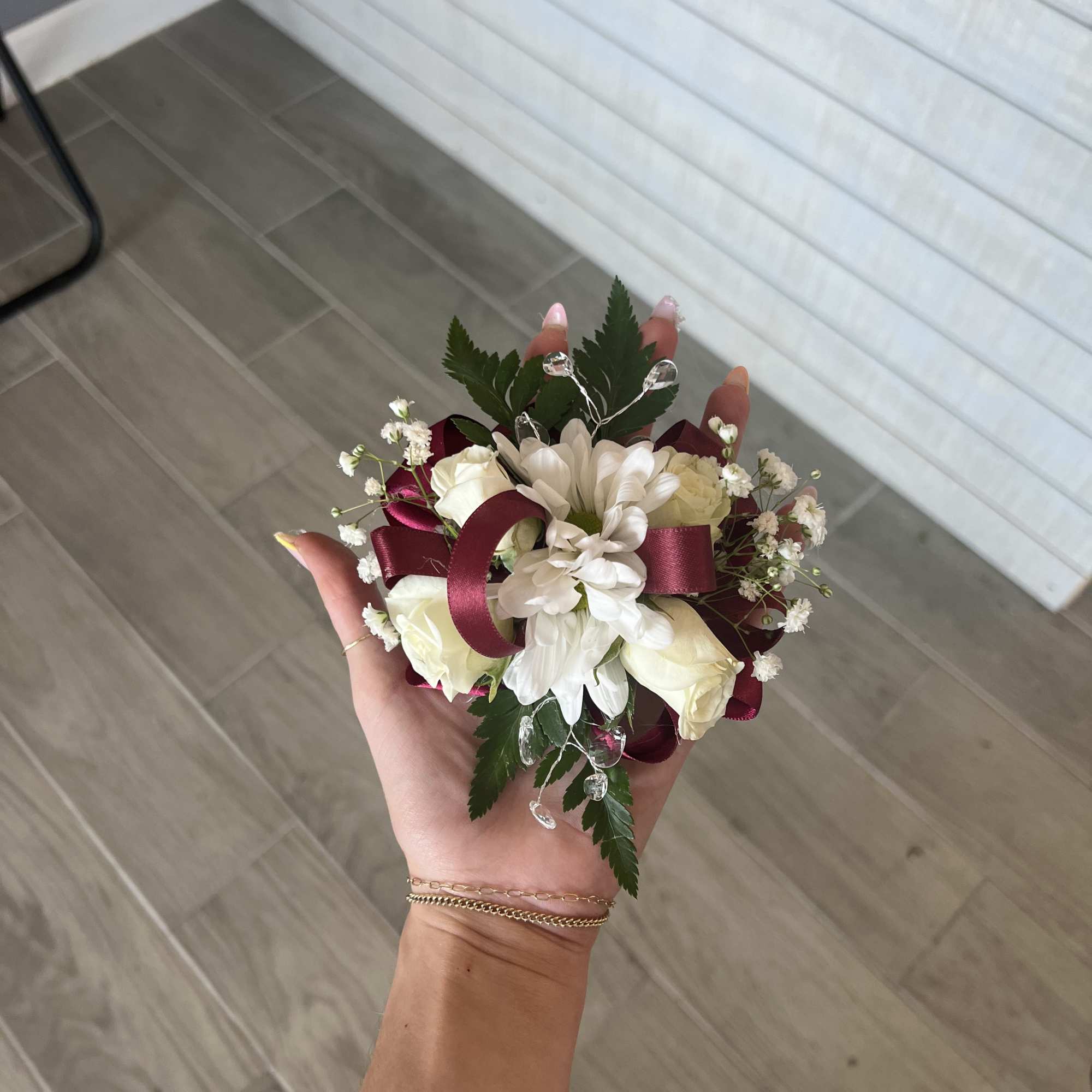 Small hand-held bouquet of white flowers with burgundy ribbon