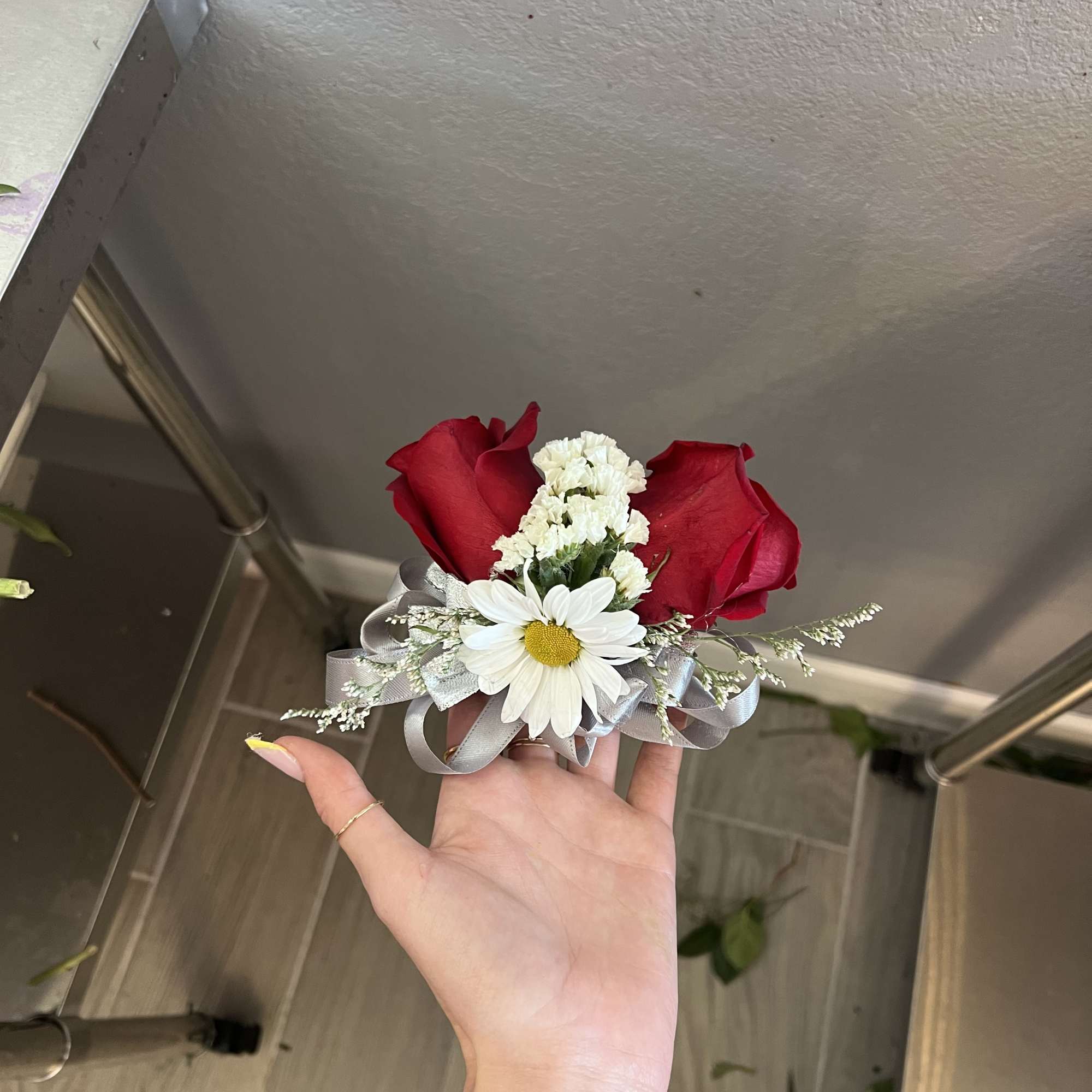 Small bouquet with red roses and a white daisy tied with silver ribbon