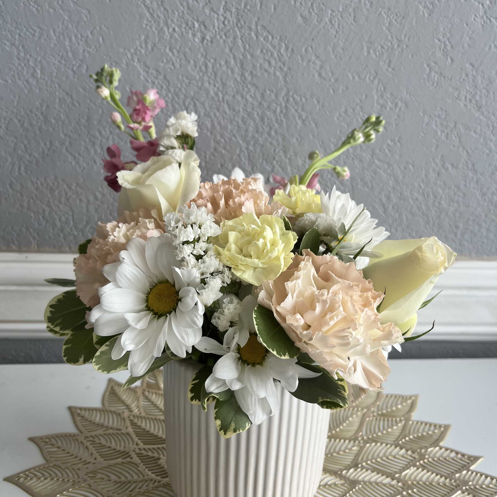 Pastel flower arrangement in a ribbed white vase