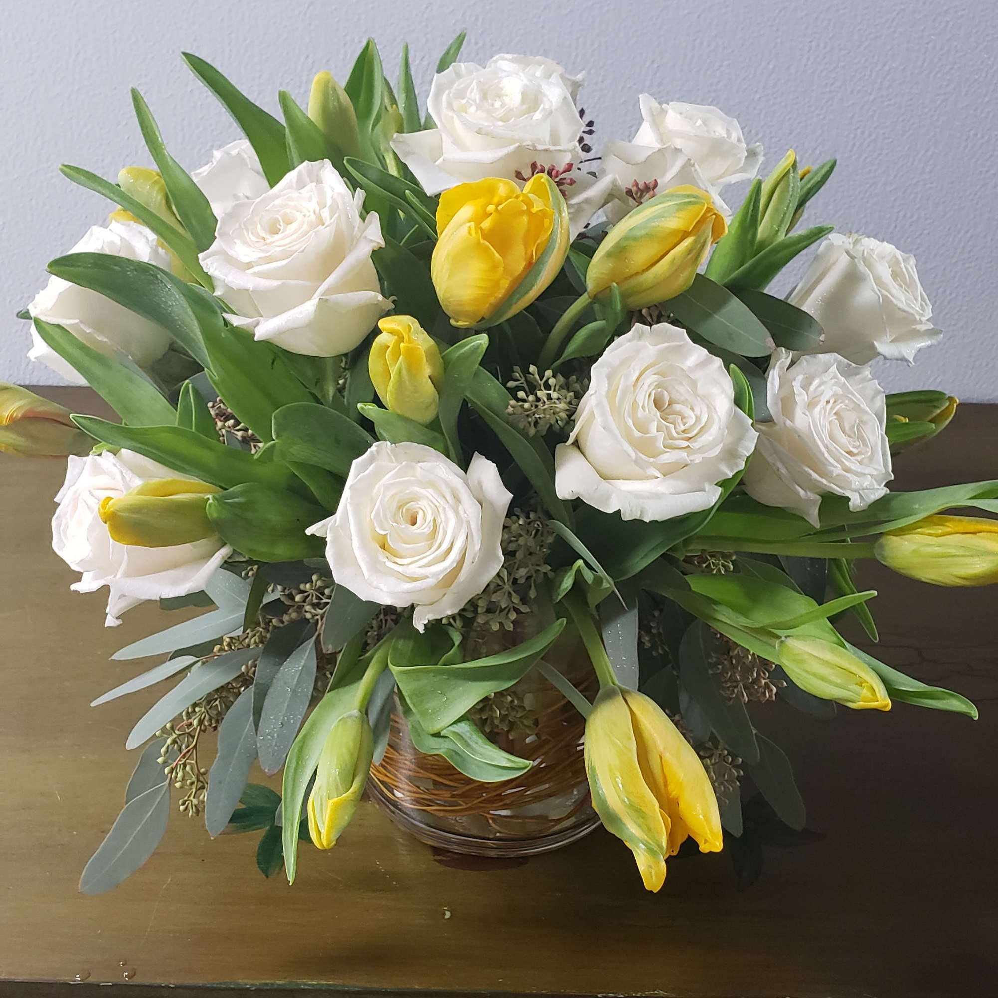 White roses and yellow tulips arranged in a glass bowl