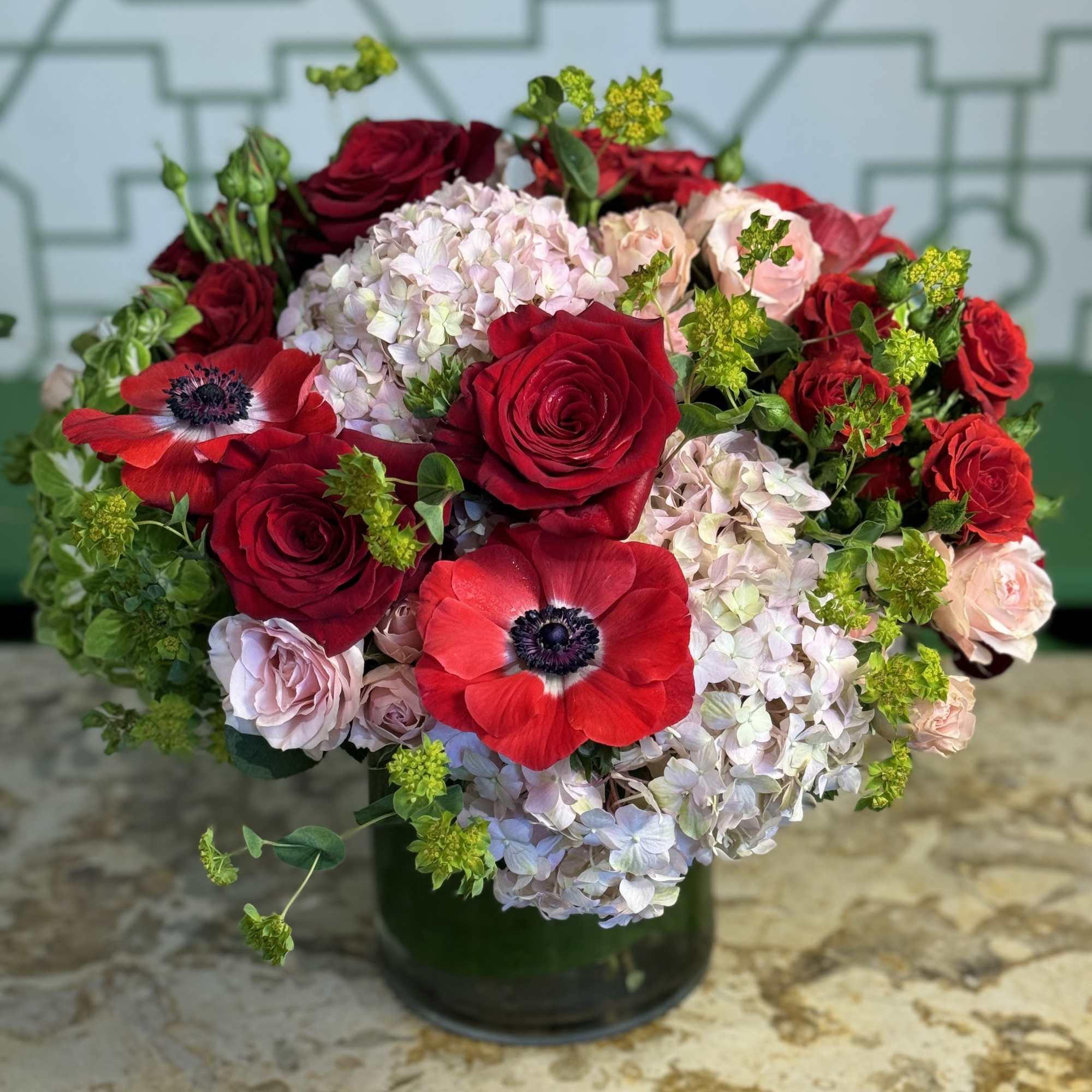 Red roses and pale hydrangeas in a dark glass vase