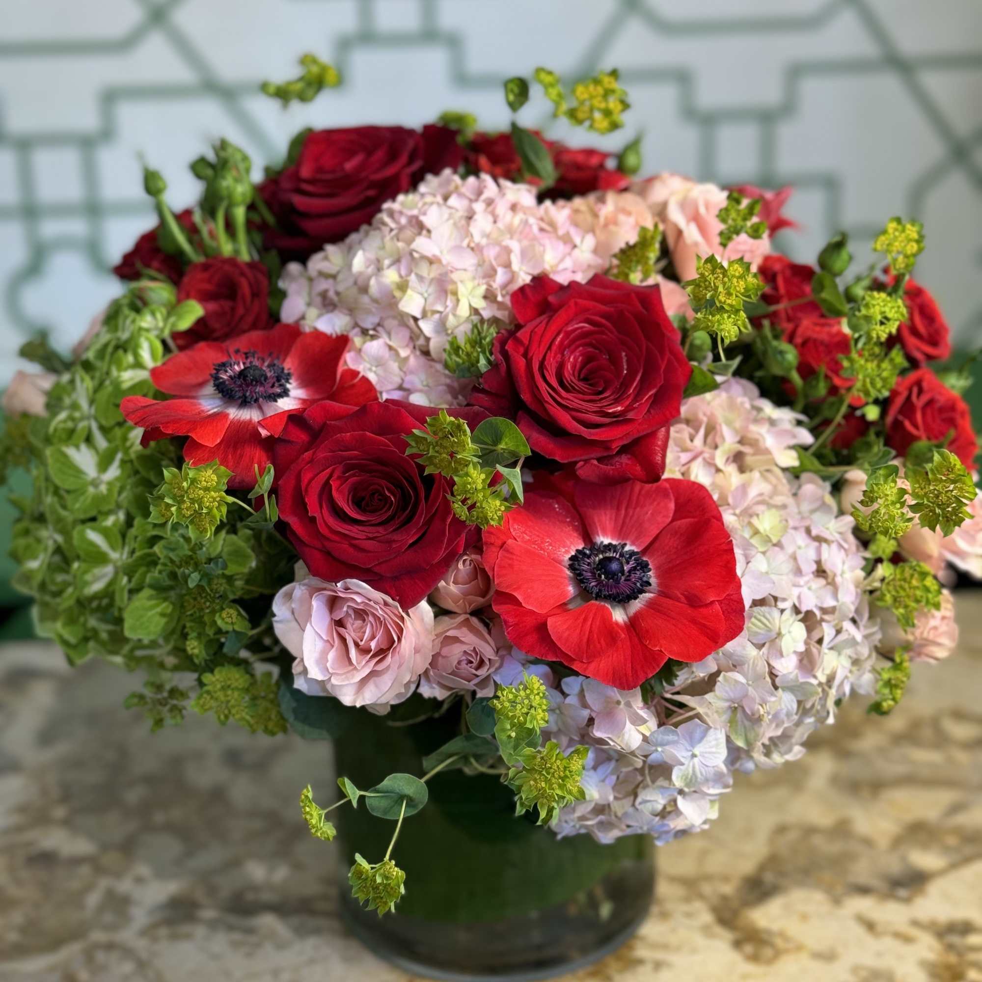Red roses and pale hydrangeas arranged in a dark vase