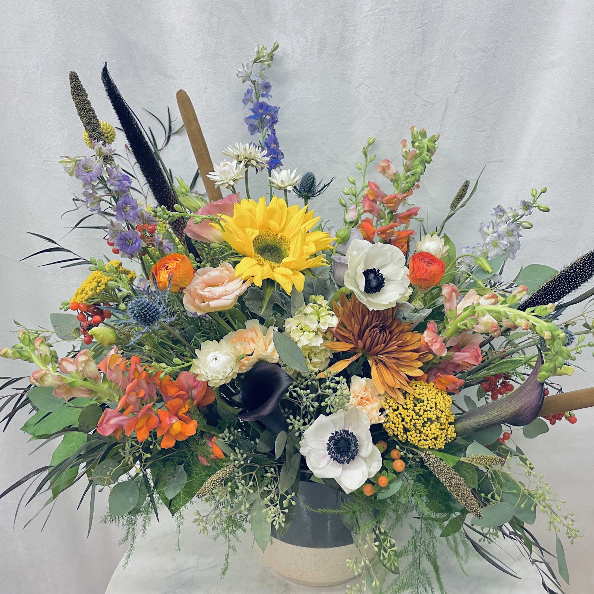 Mixed bouquet with sunflowers, anemones, and orange blooms in a vase