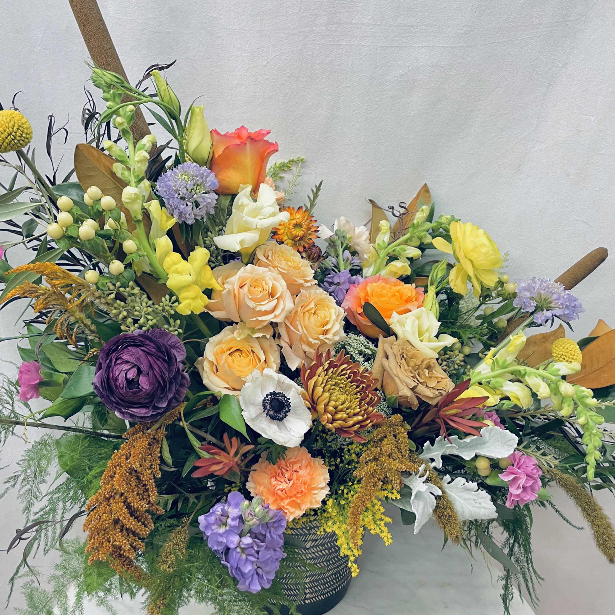 Large mixed bouquet with roses, mums, and assorted blooms in a dark vase