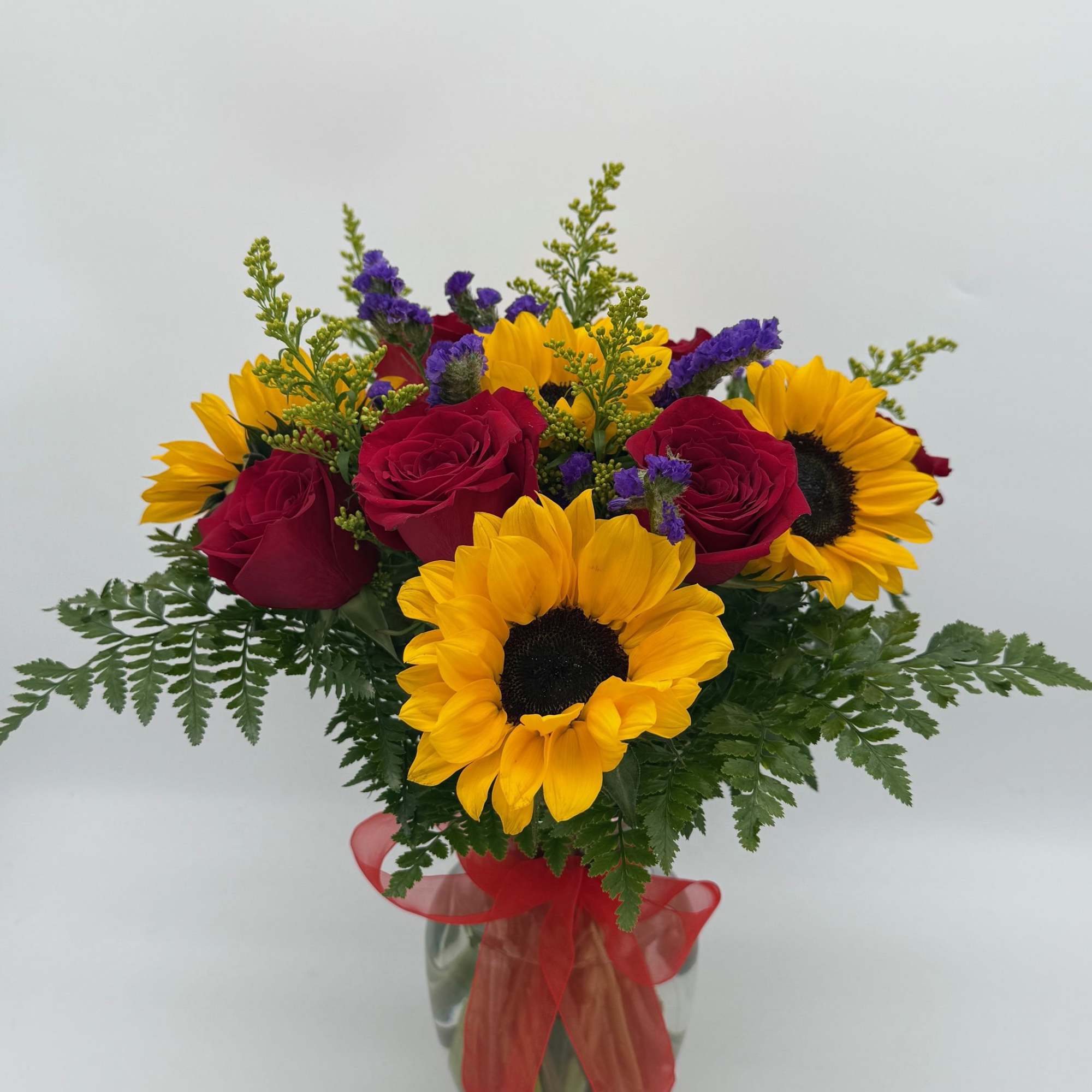 Bouquet of red roses and yellow sunflowers in a glass vase