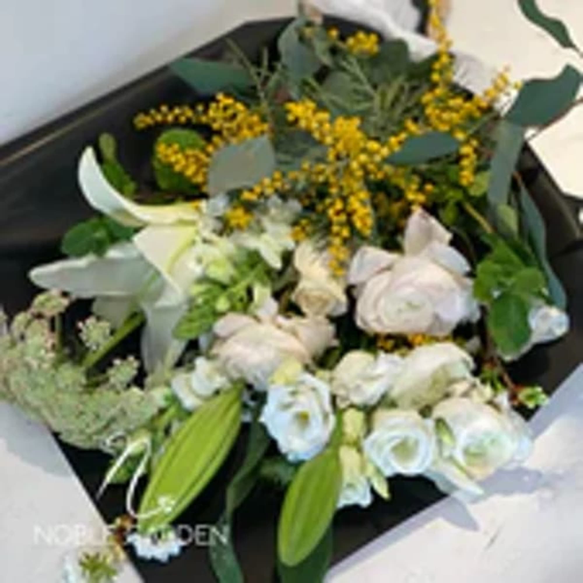 White roses and lilies with yellow blossoms in a black box
