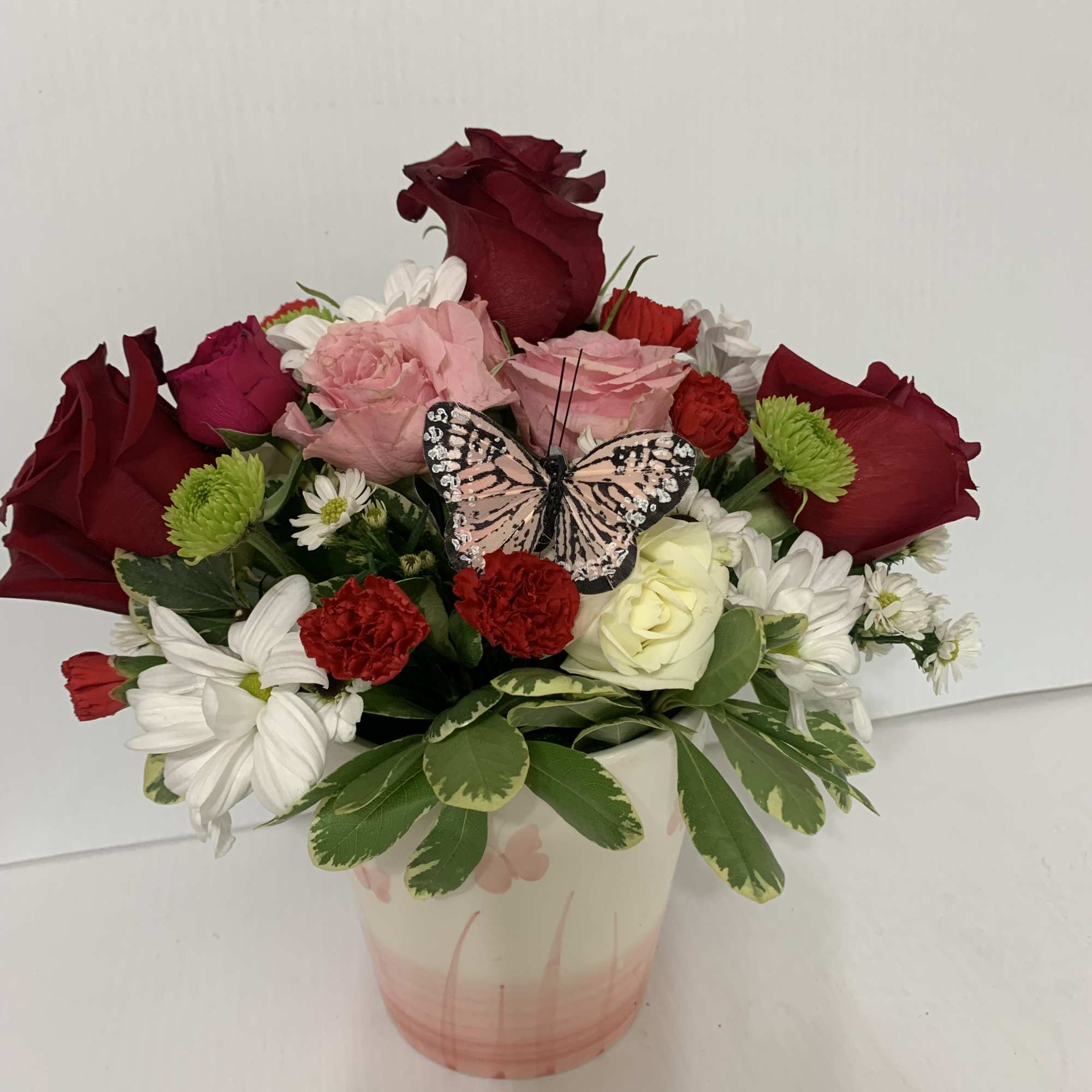 Mixed bouquet in a pink vase with a butterfly decoration