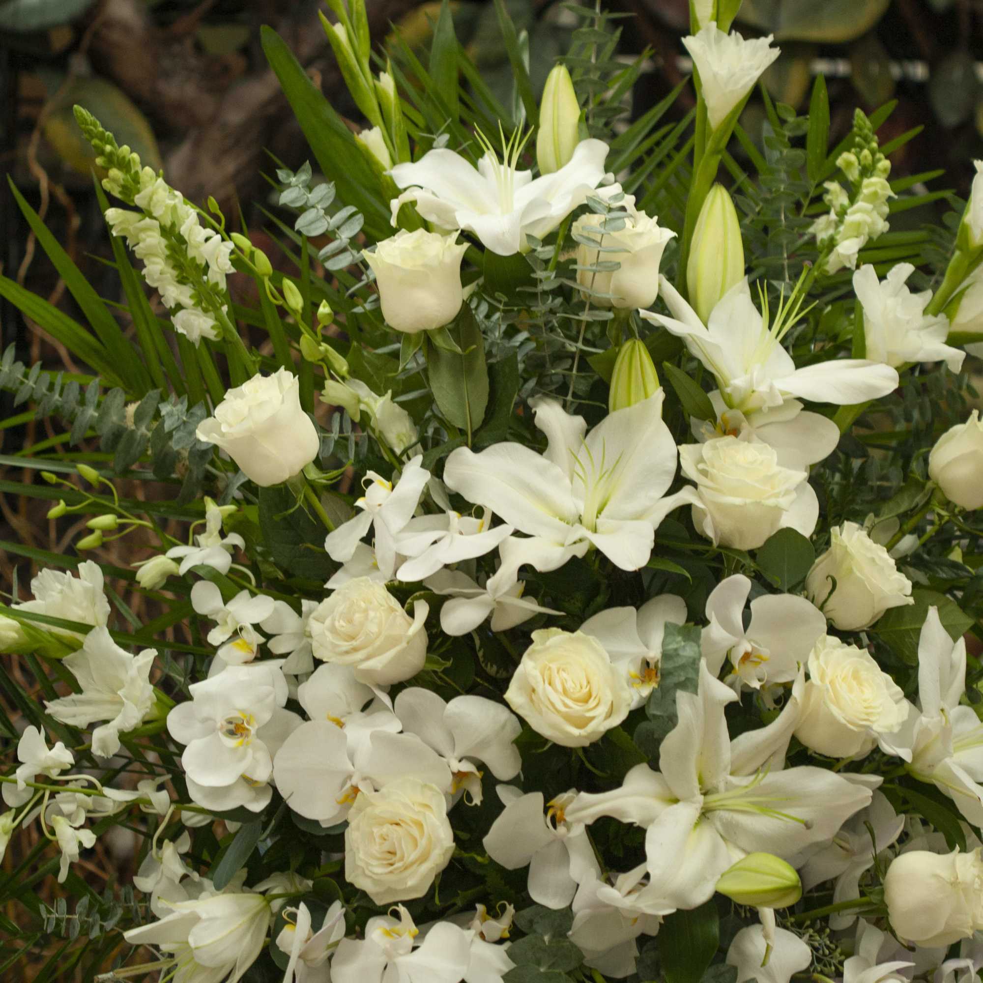 White floral arrangement with lilies, roses, and orchids