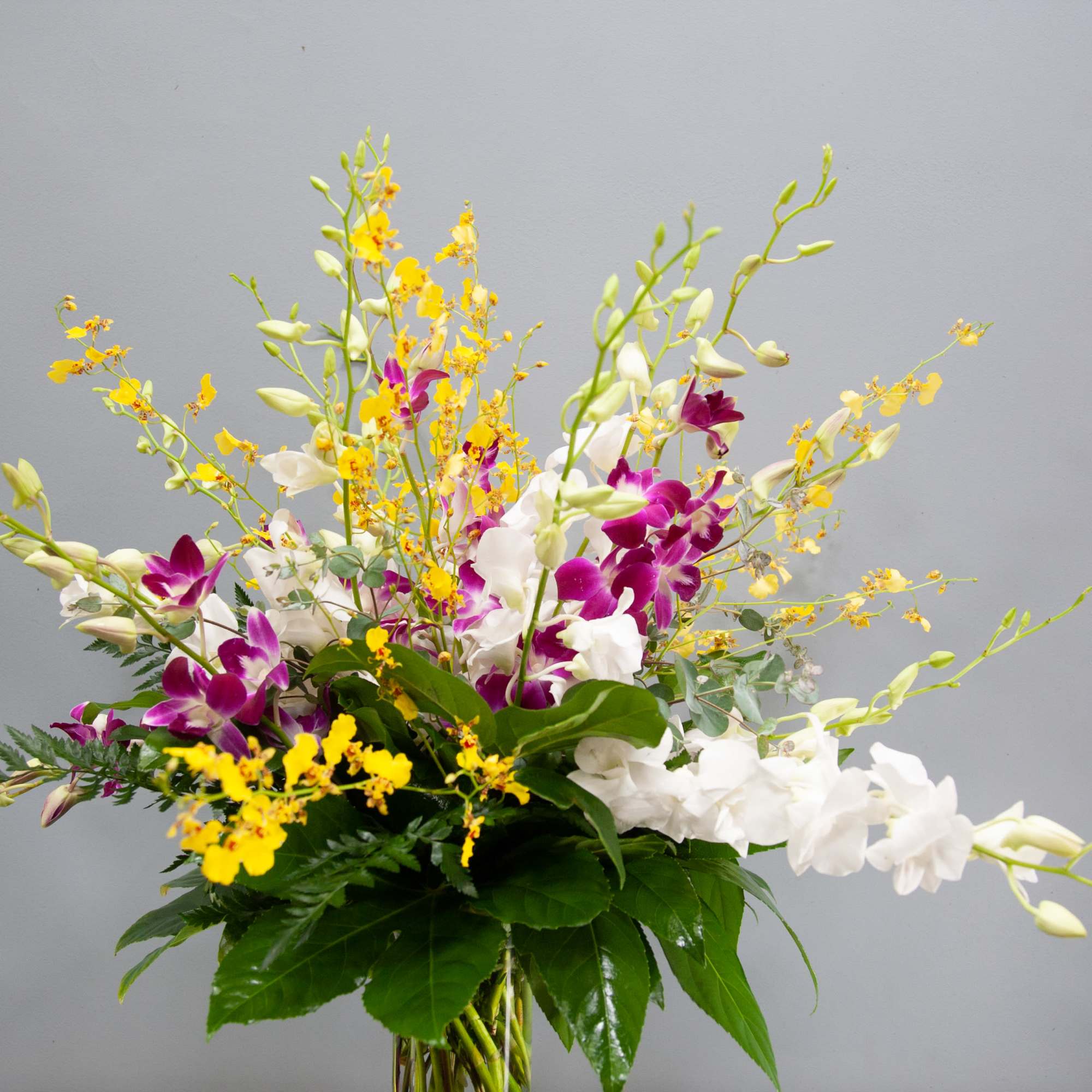 Tall bouquet of white and purple orchids with yellow accents