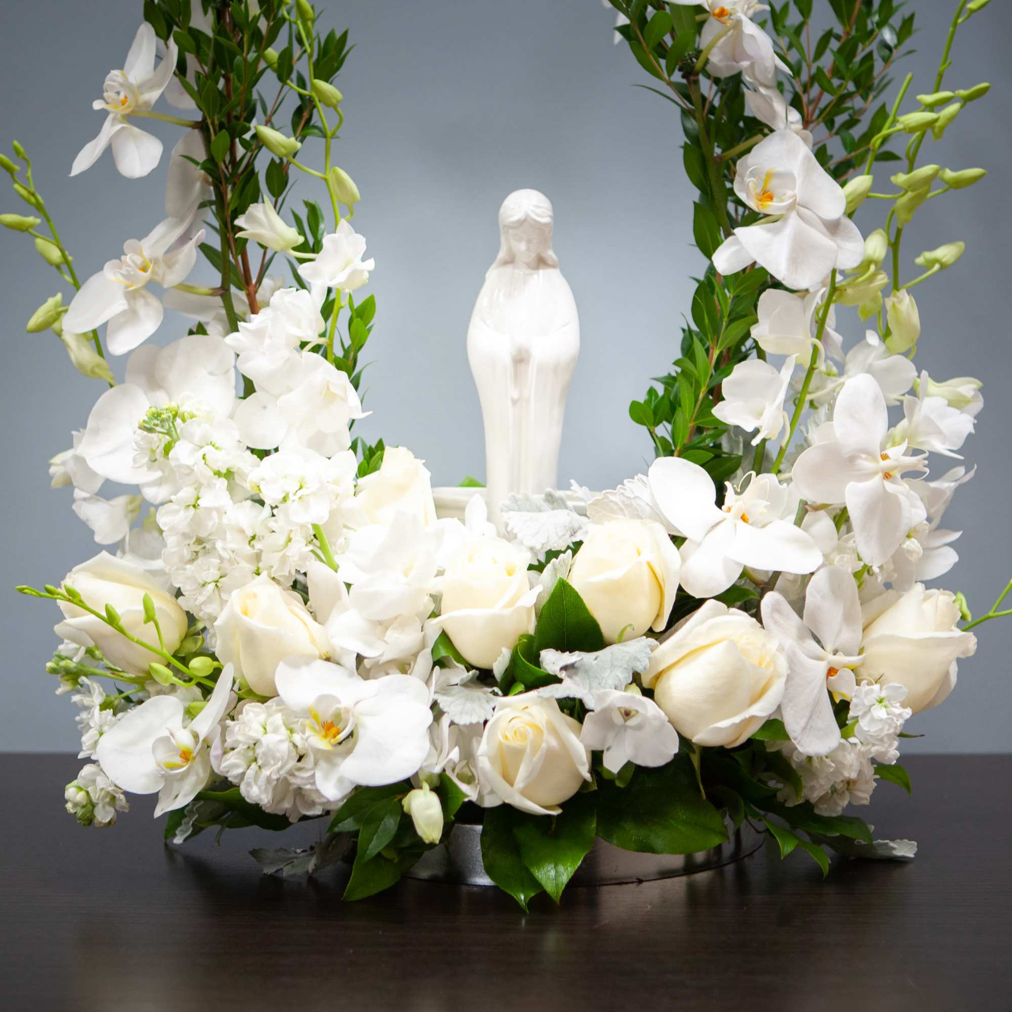 White floral arrangement with a central statue on a low base