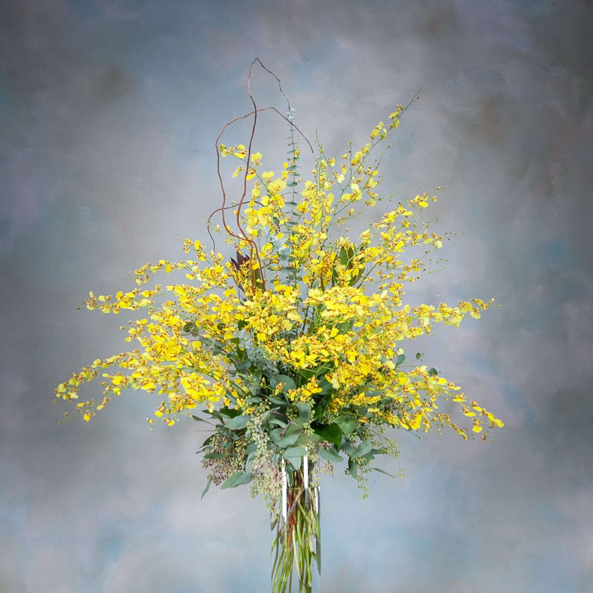 Tall yellow flower arrangement in a clear glass vase
