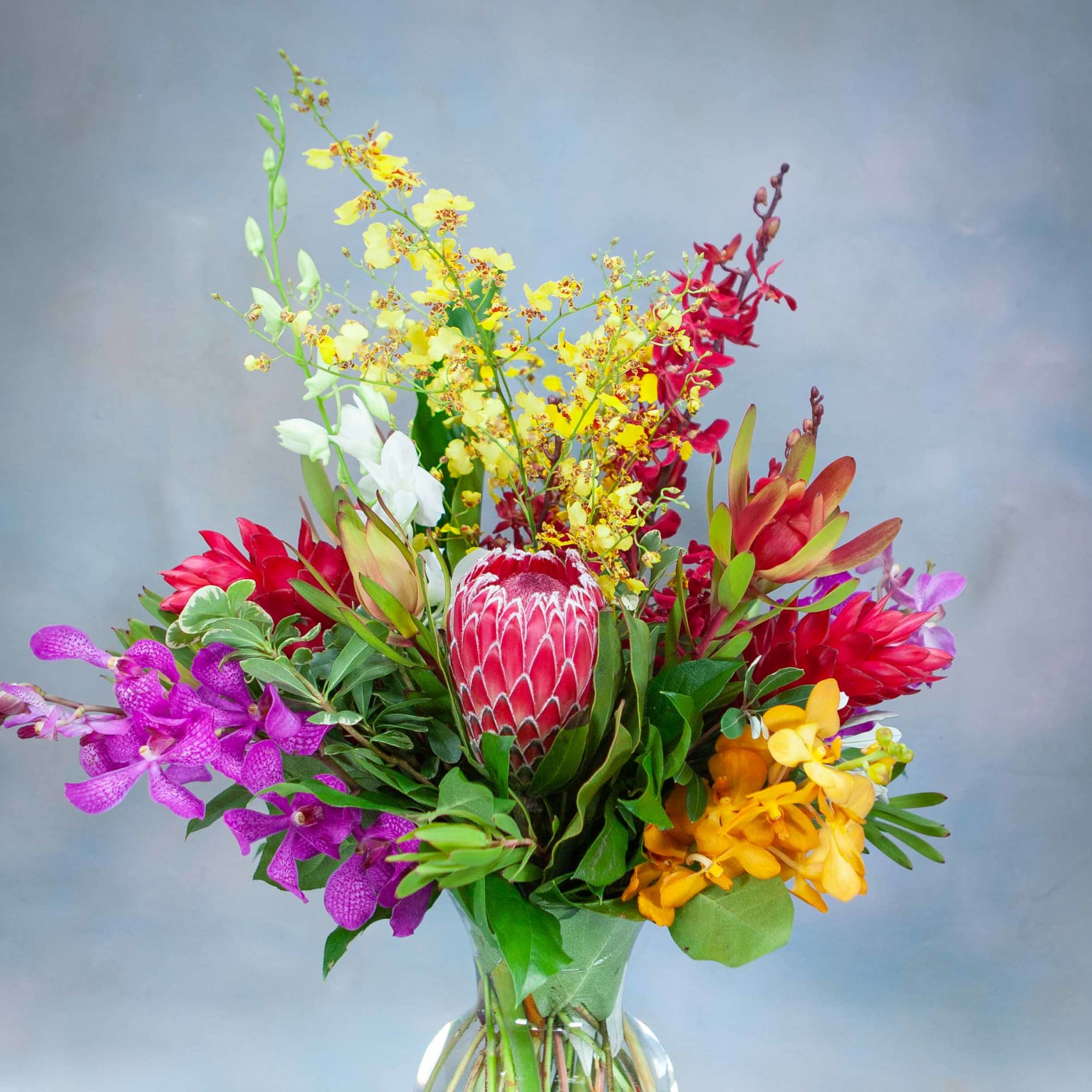 Colorful mixed orchid bouquet in a clear glass vase