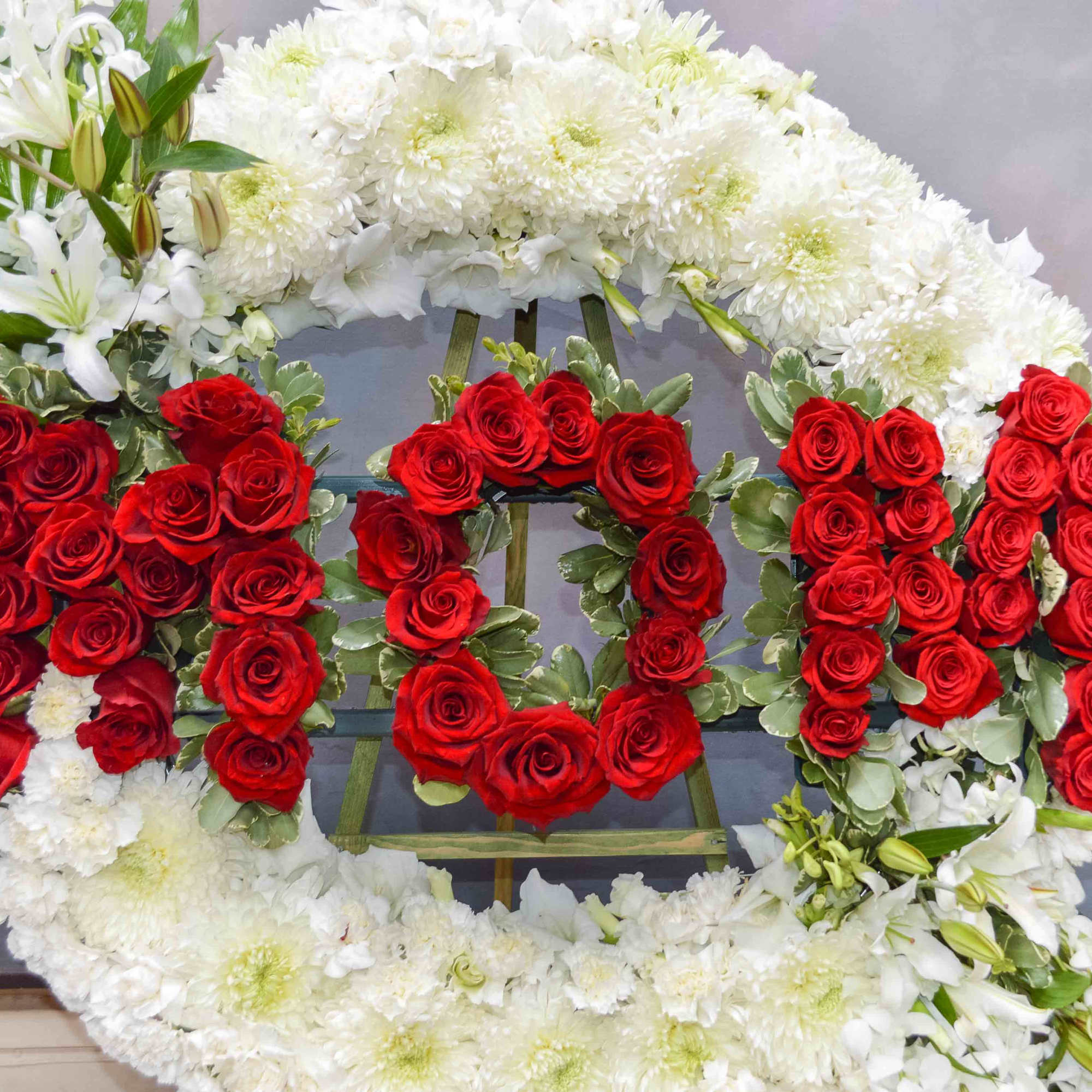 Floral wreath with red roses and white chrysanthemums arranged around the word LOVE