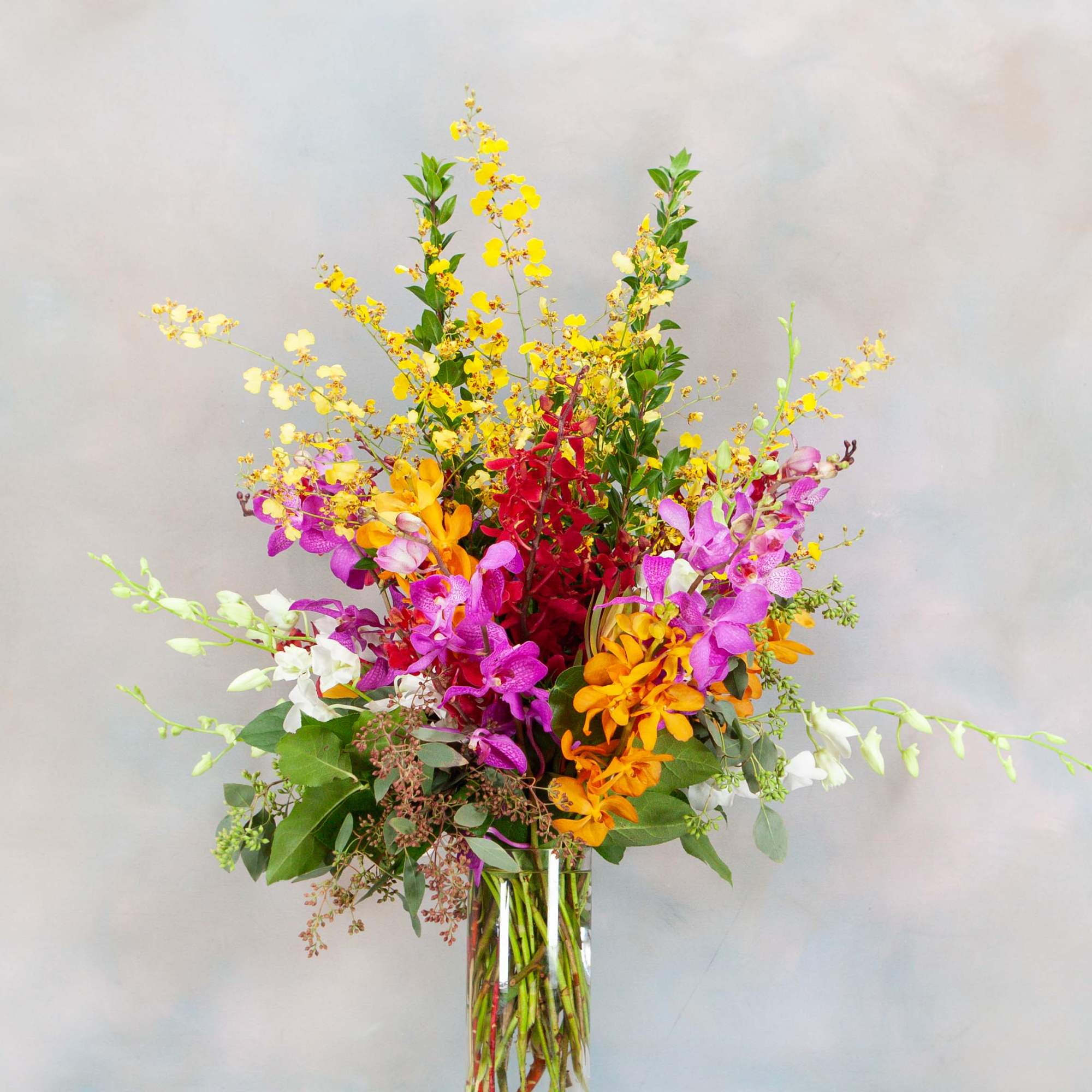 Tall mixed orchid arrangement in a clear glass vase, photo 2 of 2