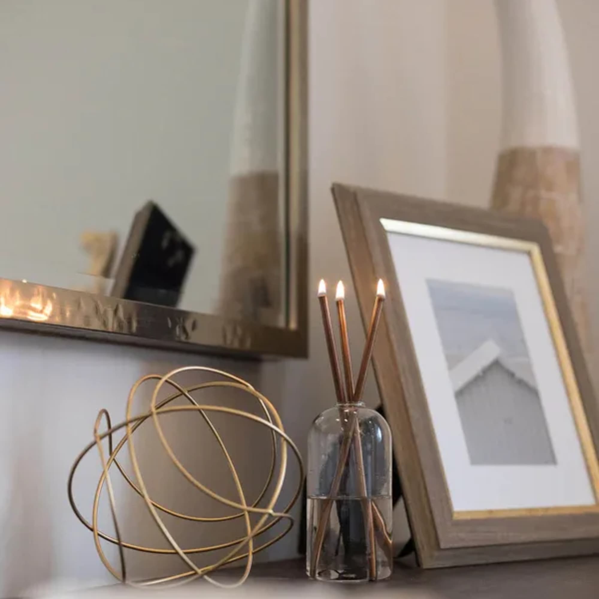 Decorative reed diffuser with framed photos and a metal sculpture