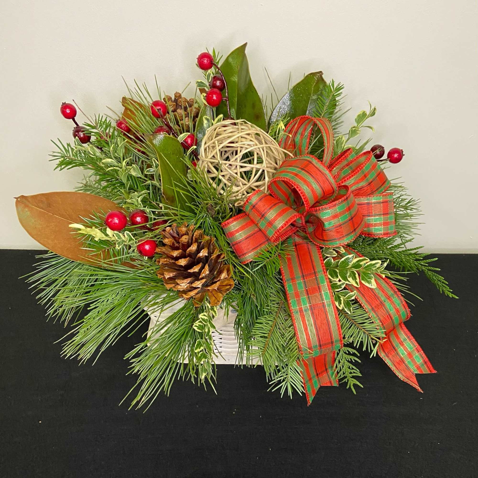 Mixed wintergreens and pine cones accented with deep red berries and a