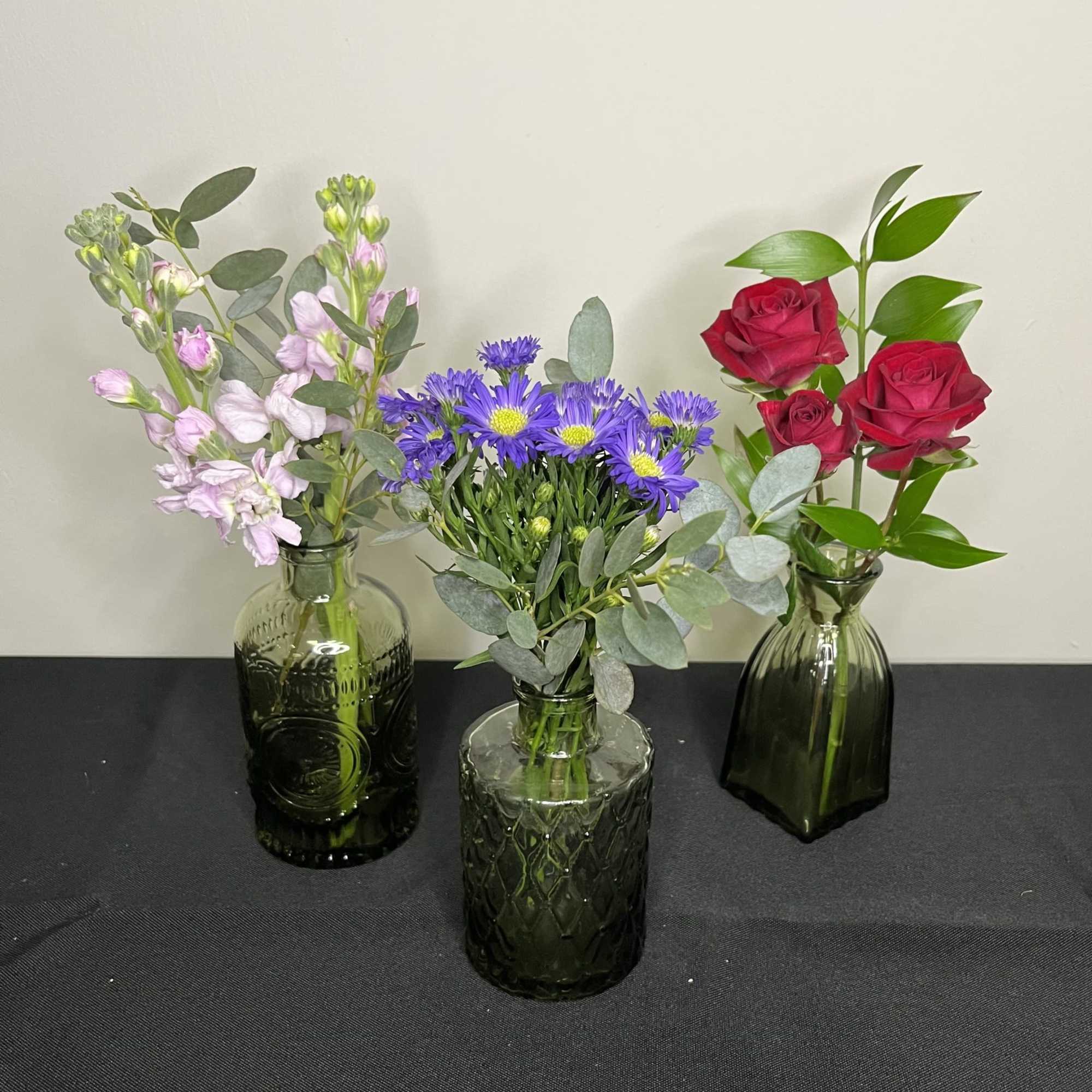 A selection of 3 bud vases with assorted flowers in each. 