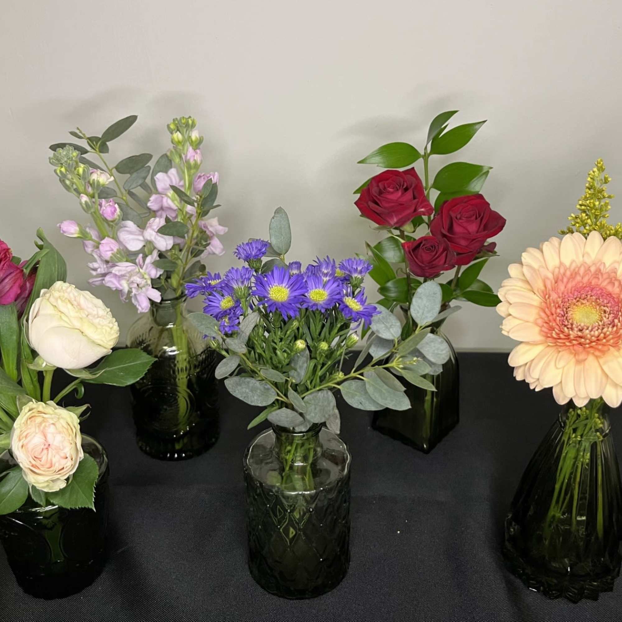 A selection of 3 bud vases with assorted flowers in each. 
