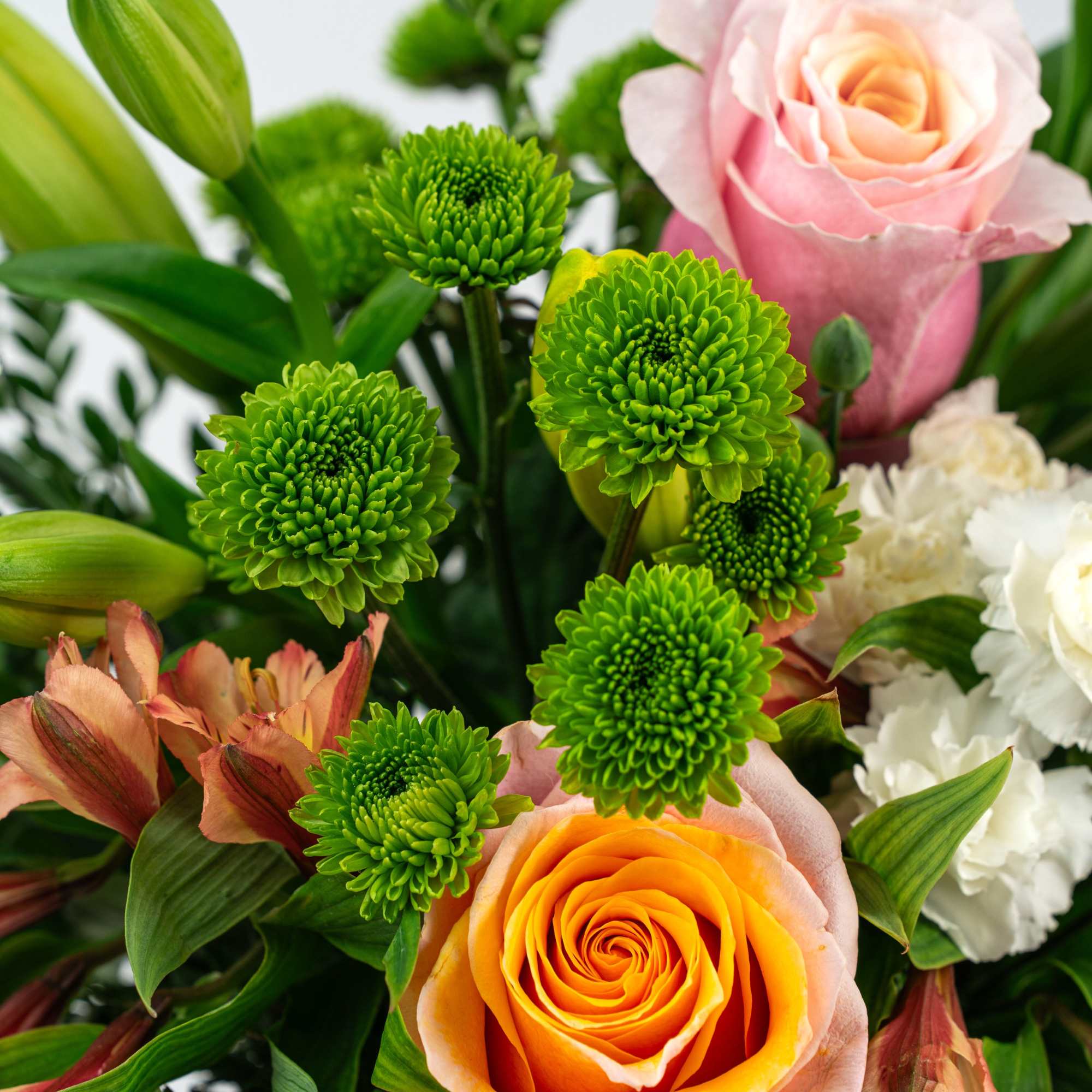 Mixed bouquet with orange and pink roses, green button mums, lilies, and white carnations