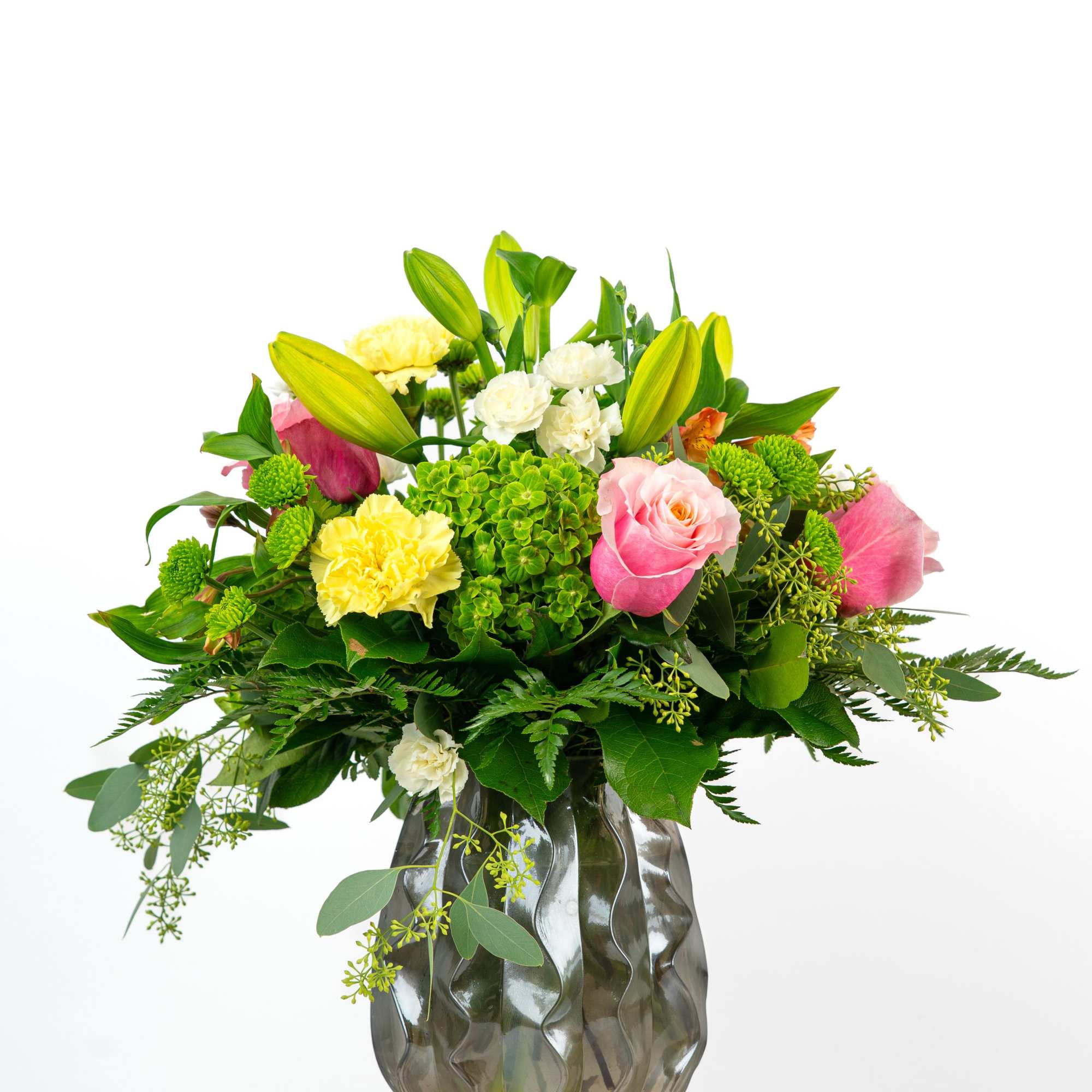 Mixed bouquet of pink roses, yellow lilies and carnations in a smoky gray glass vase