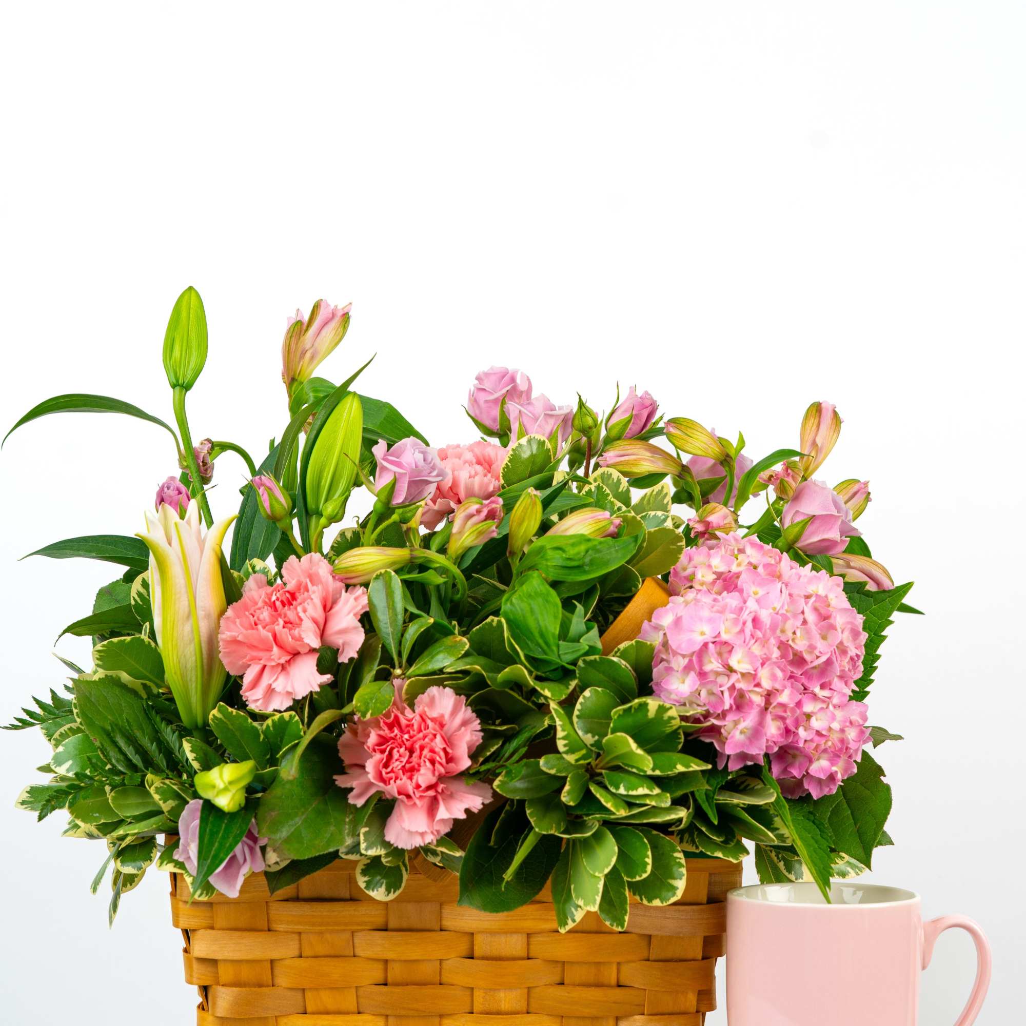 Pink flowers in a wicker basket beside a pink mug