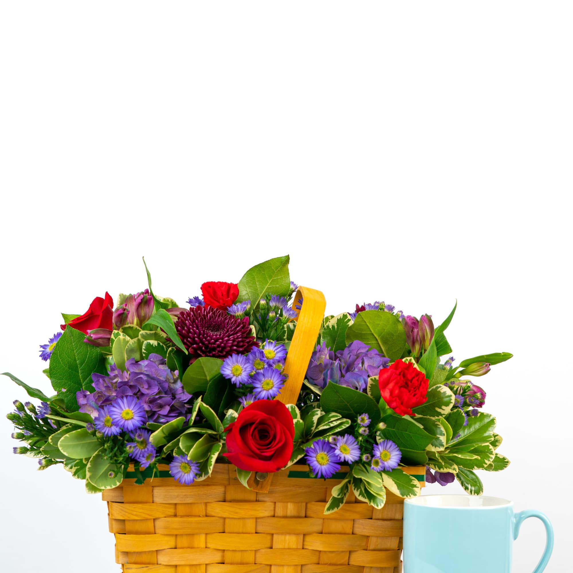 Mixed flower basket with red roses, purple blooms, and a blue mug