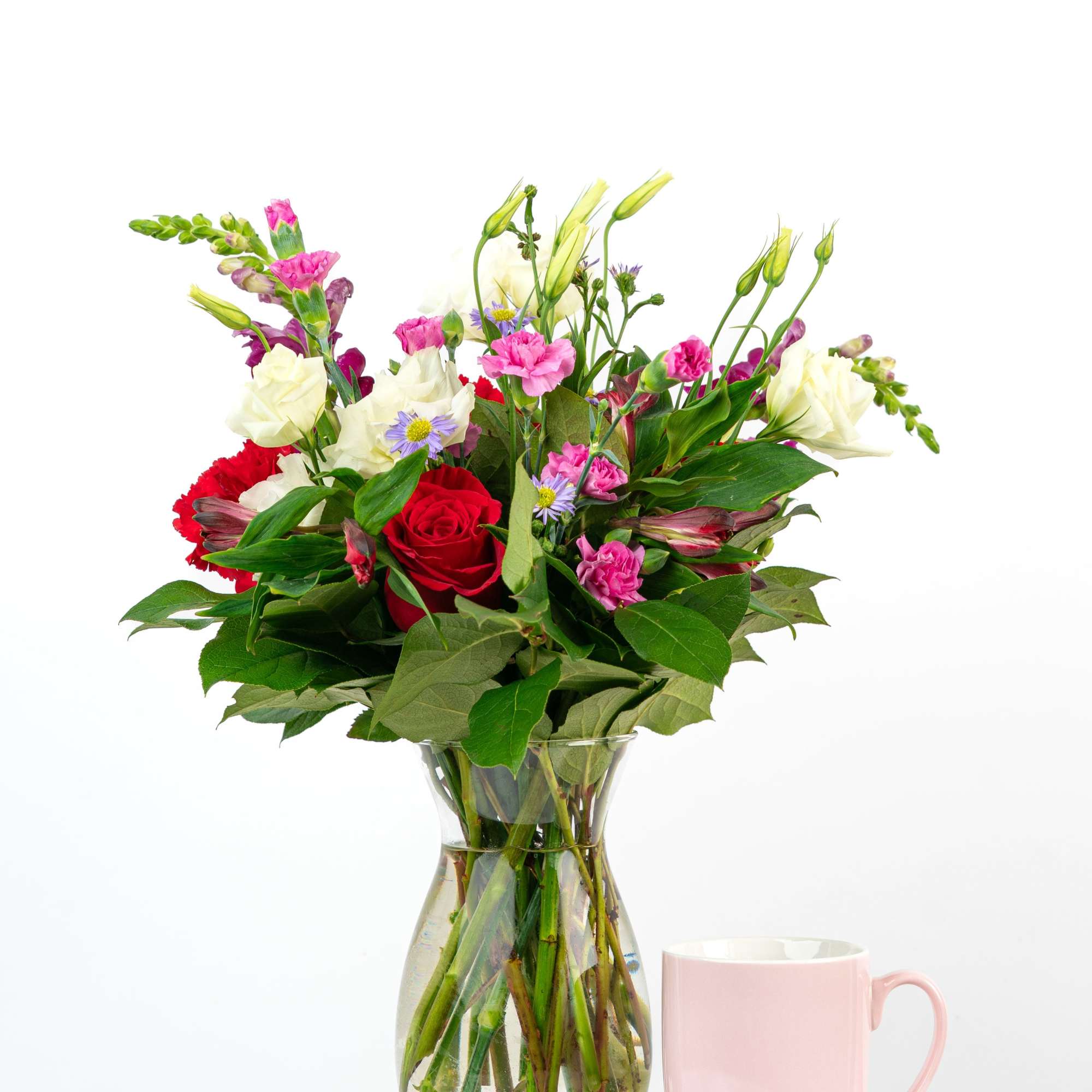 Mixed bouquet of red, pink, and white flowers in a glass vase
