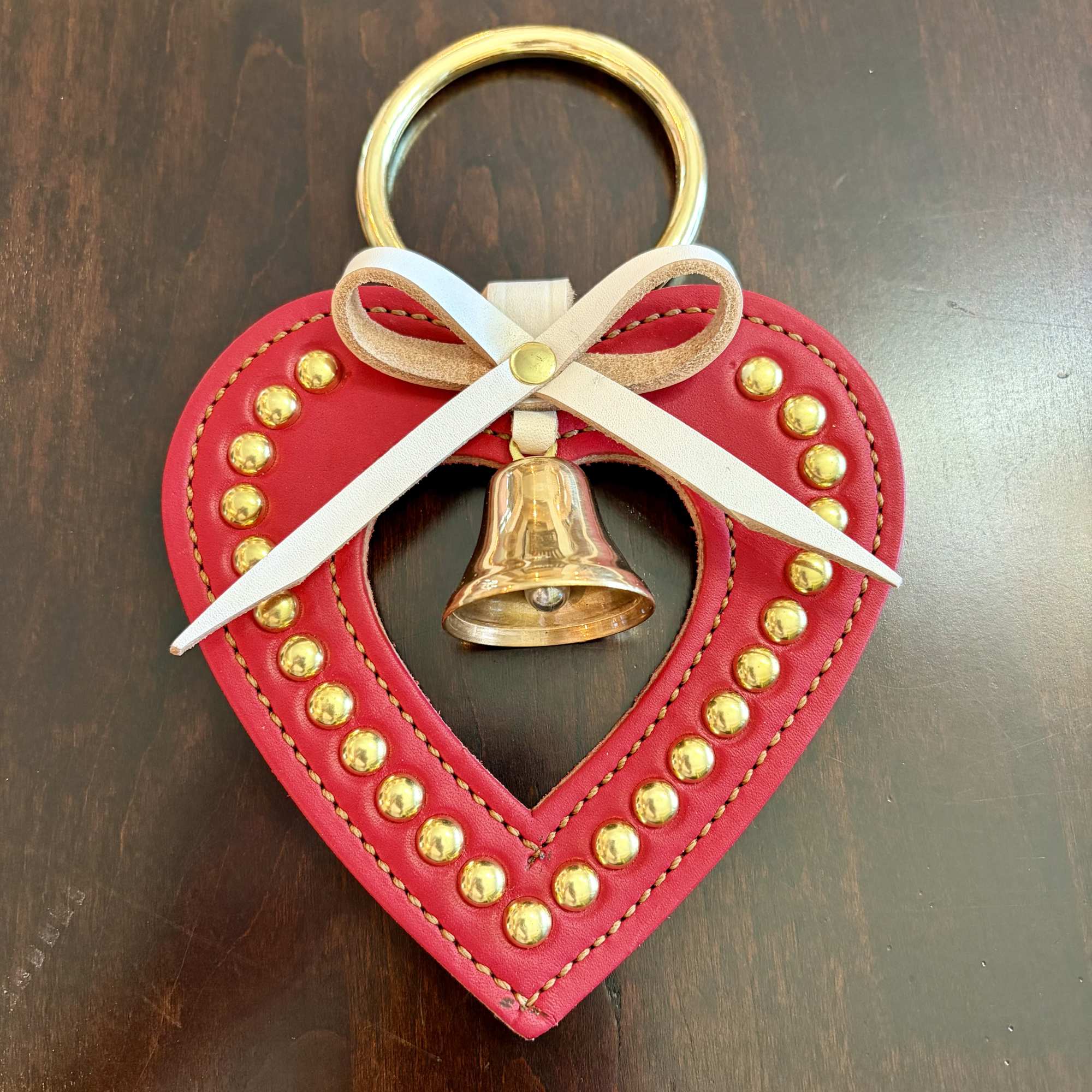 Heart-shaped red hanging ornament with a gold bell and white ribbon bow