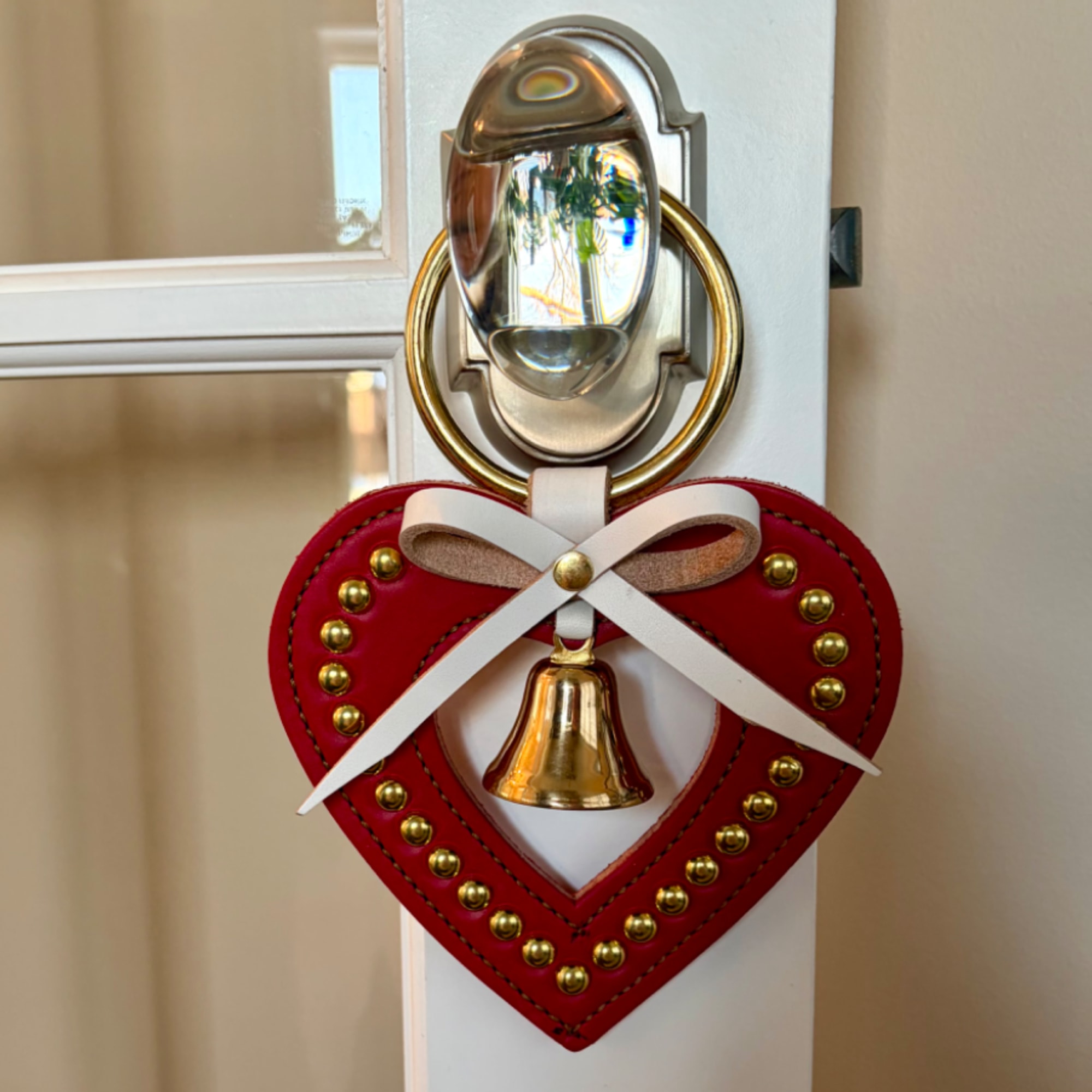 Red heart-shaped door hanger with a white bow and brass bell