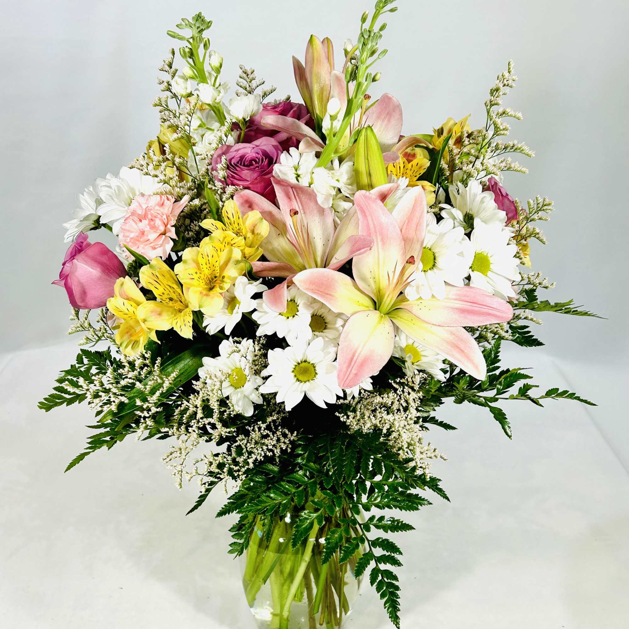 Soft lavender roses and pale pink lilies mingle with sunny yellow alstroemeria