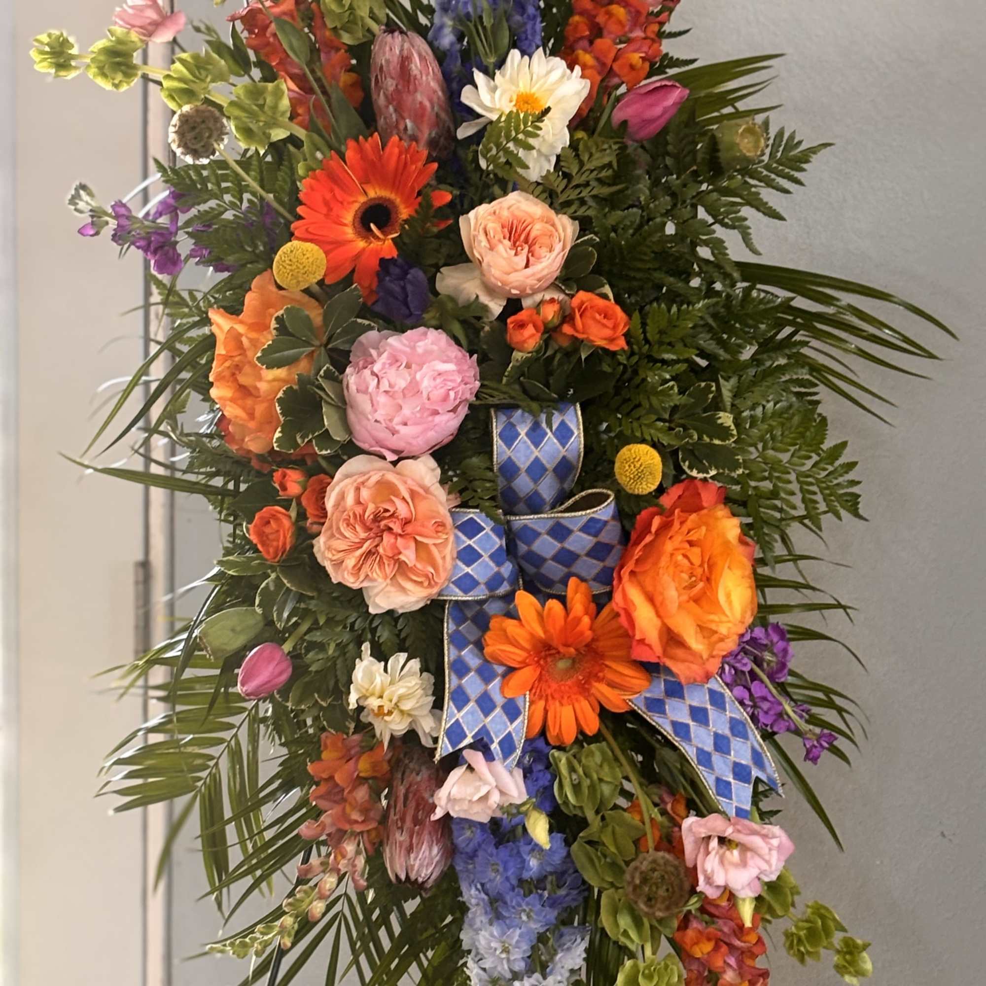 A bold, tall standing floral spray that reads like a joyous, ceremonial
