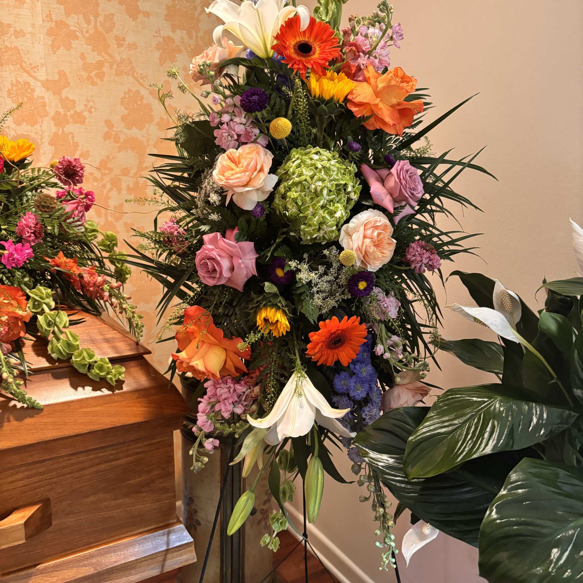 Bright, tall, and unmistakably celebratory, this standing easel spray brings together lilies