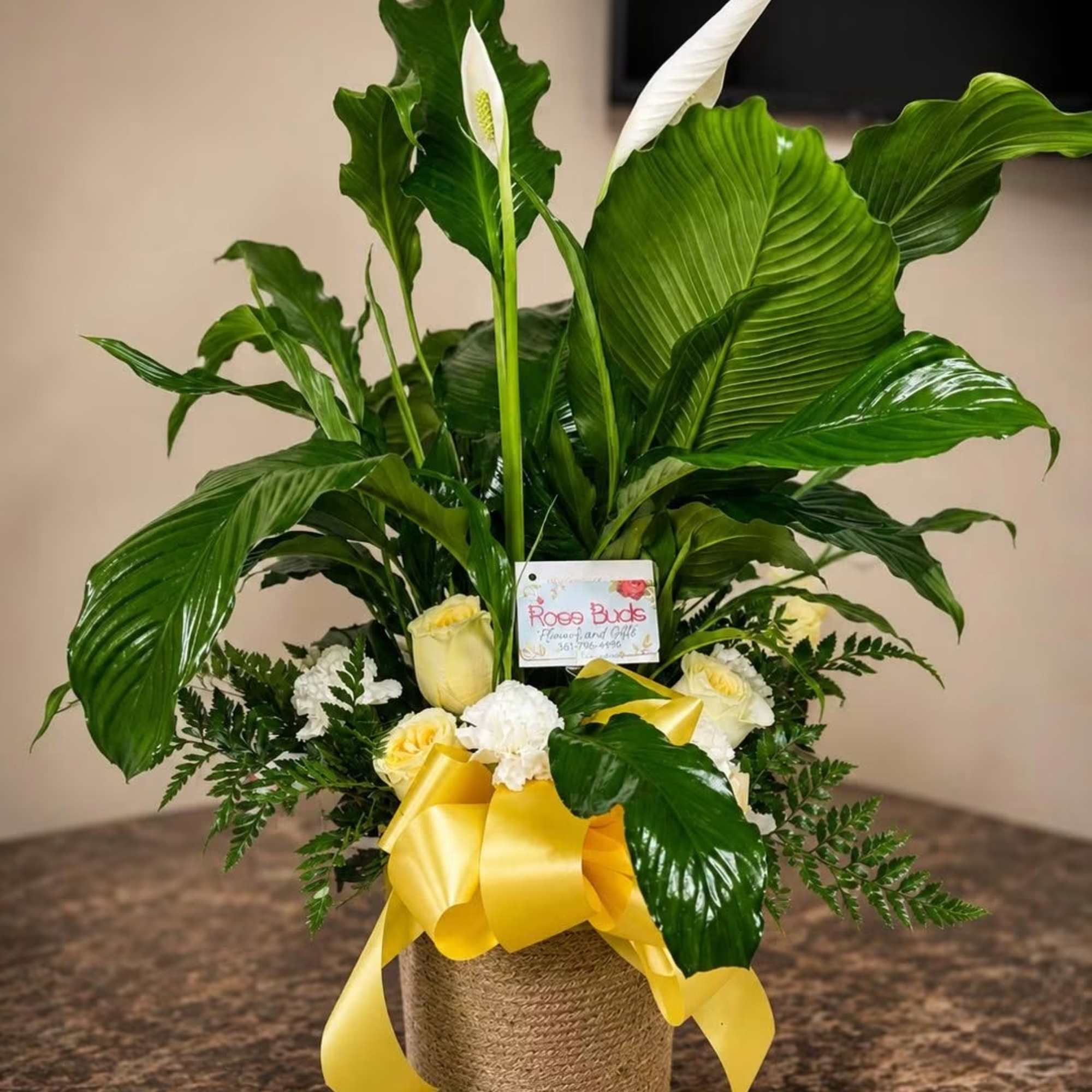 Potted peace lily arrangement with yellow roses and a yellow ribbon