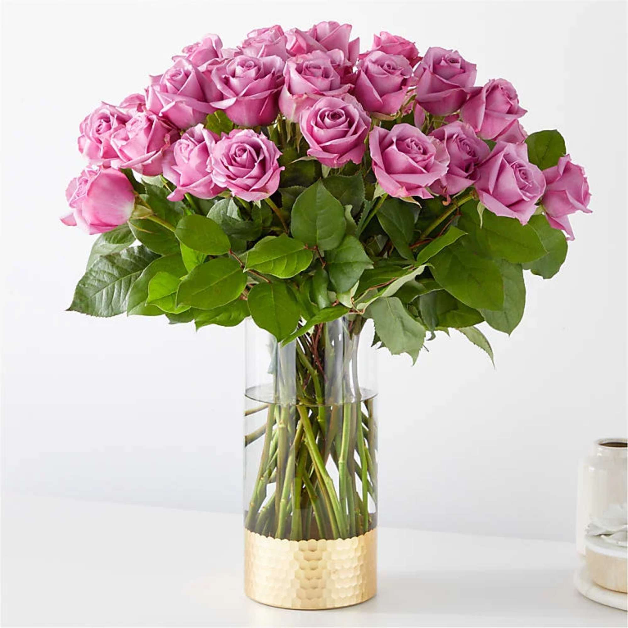Pink roses arranged in a clear glass vase with a gold base